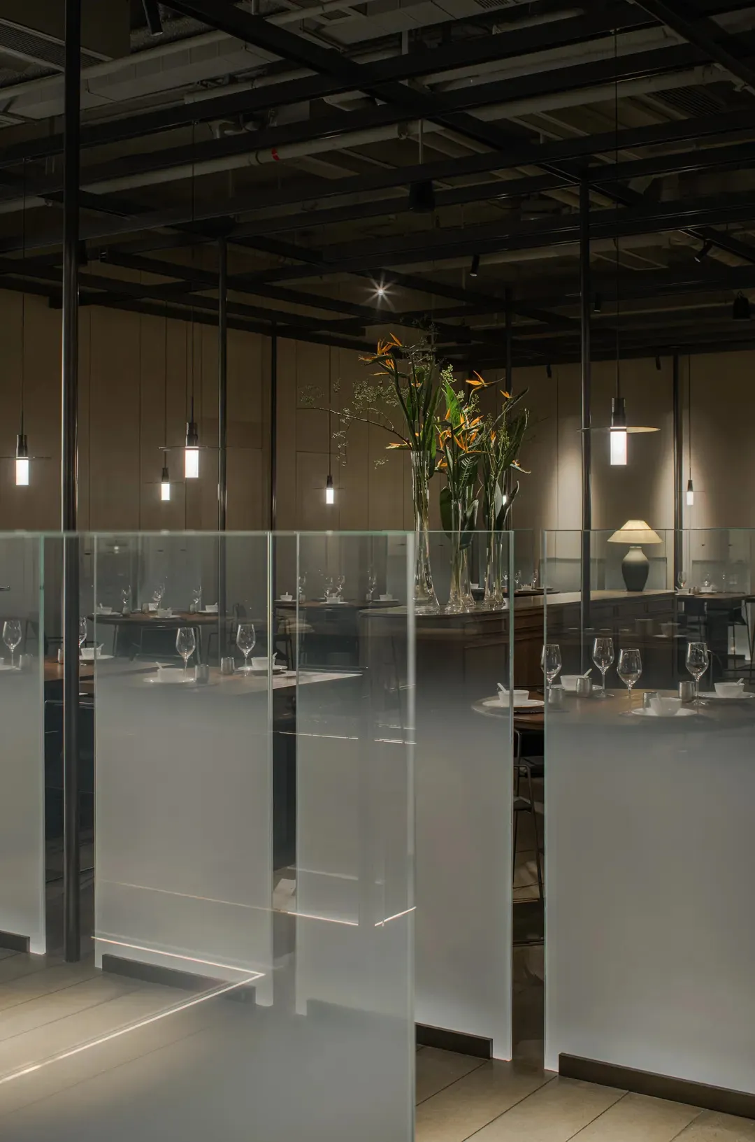 A modern restaurant interior with glass and concrete surfaces, featuring minimalist decor and a spacious layout.