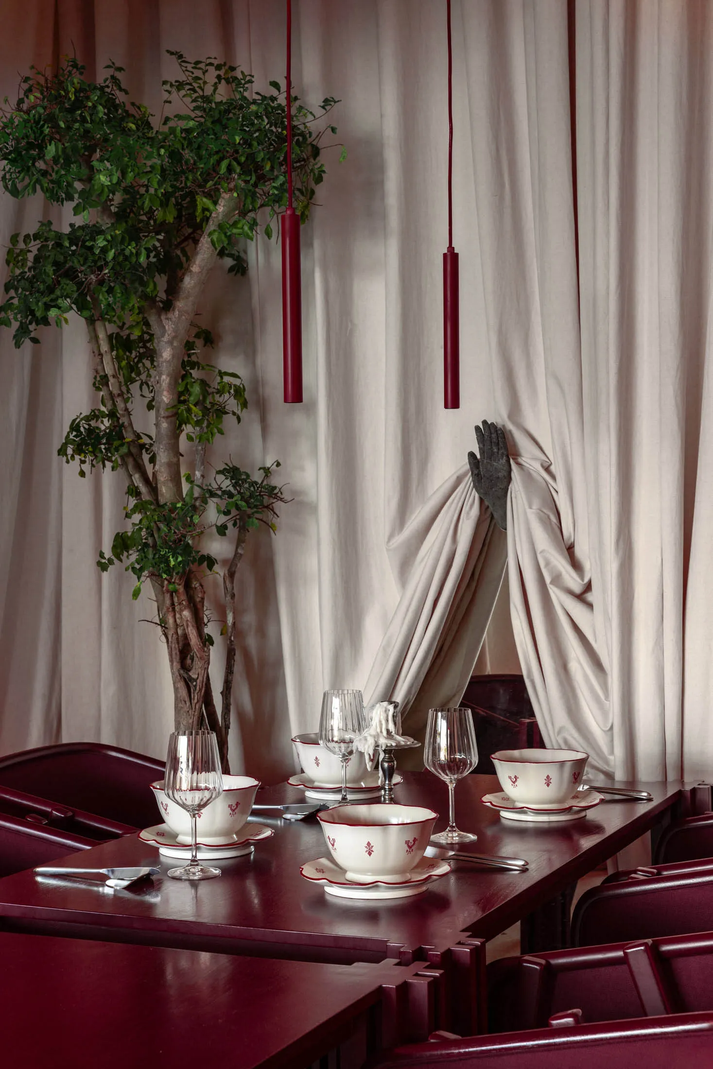 Modern restaurant interior featuring wooden furniture, glassware, and green plant.