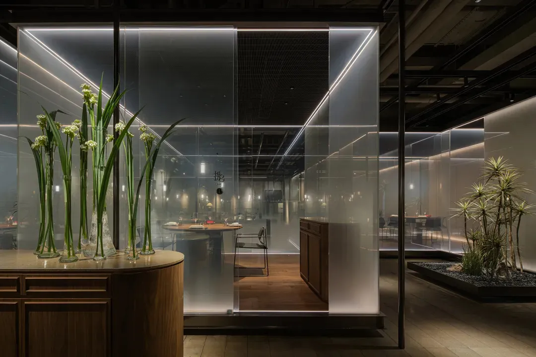 現代餐廳內設有玻璃隱私隔板，搭配木質餐桌擺設與植栽。