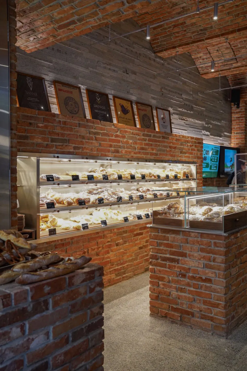 A bakery interior with exposed brick walls and a display case filled with baked goods.
