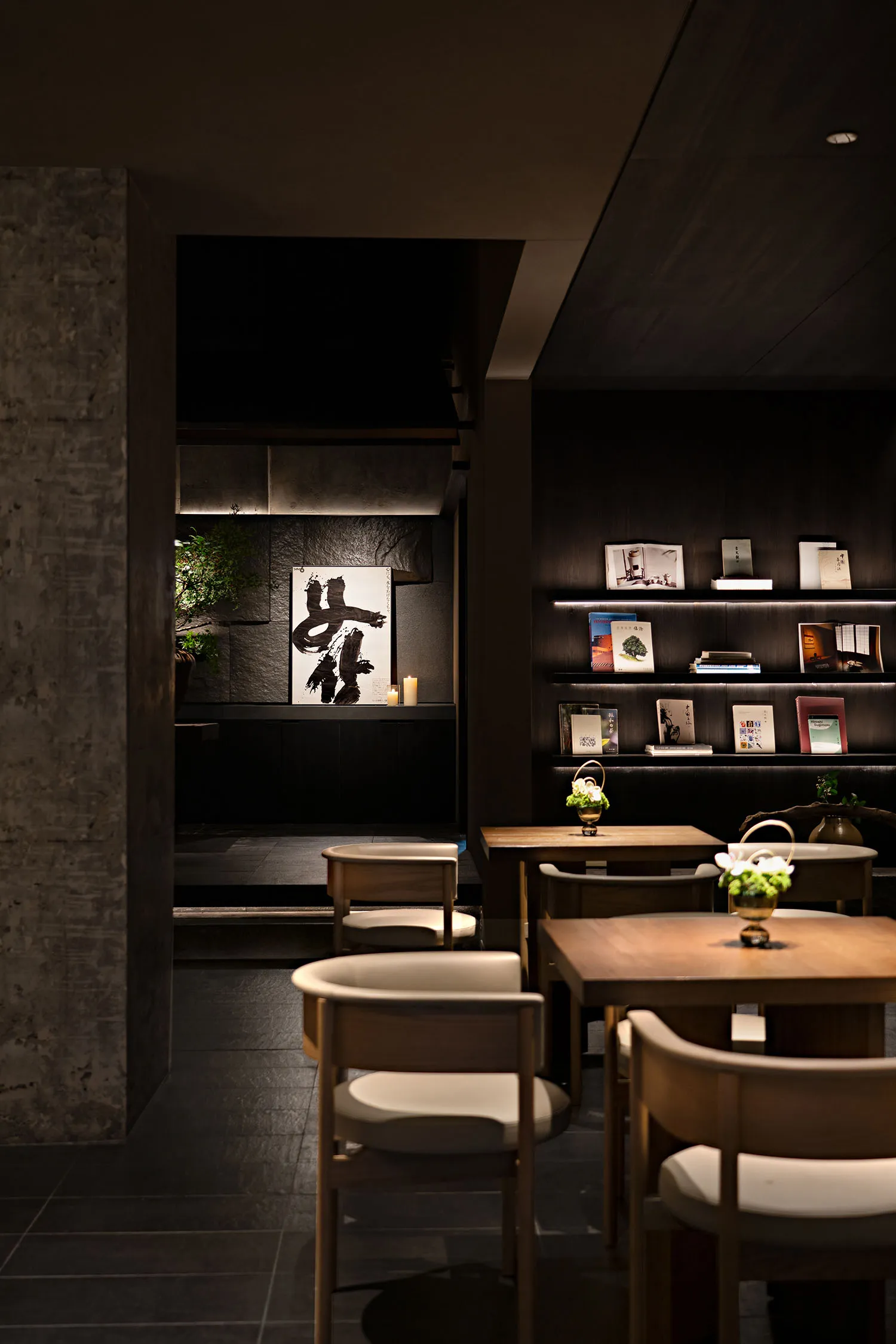 A modern cafe interior with wooden tables, fabric chairs, and concrete walls.