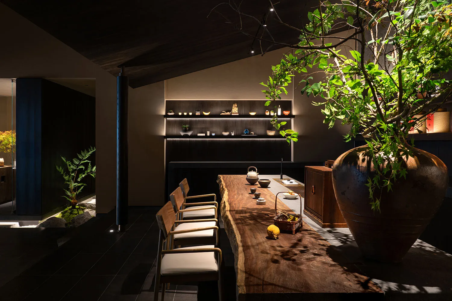 A minimalist restaurant interior with a wooden table, chairs, and shelving unit