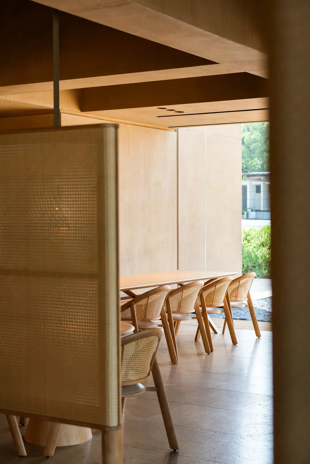 Modern restaurant seating area with cane-backed chairs and wooden tables.