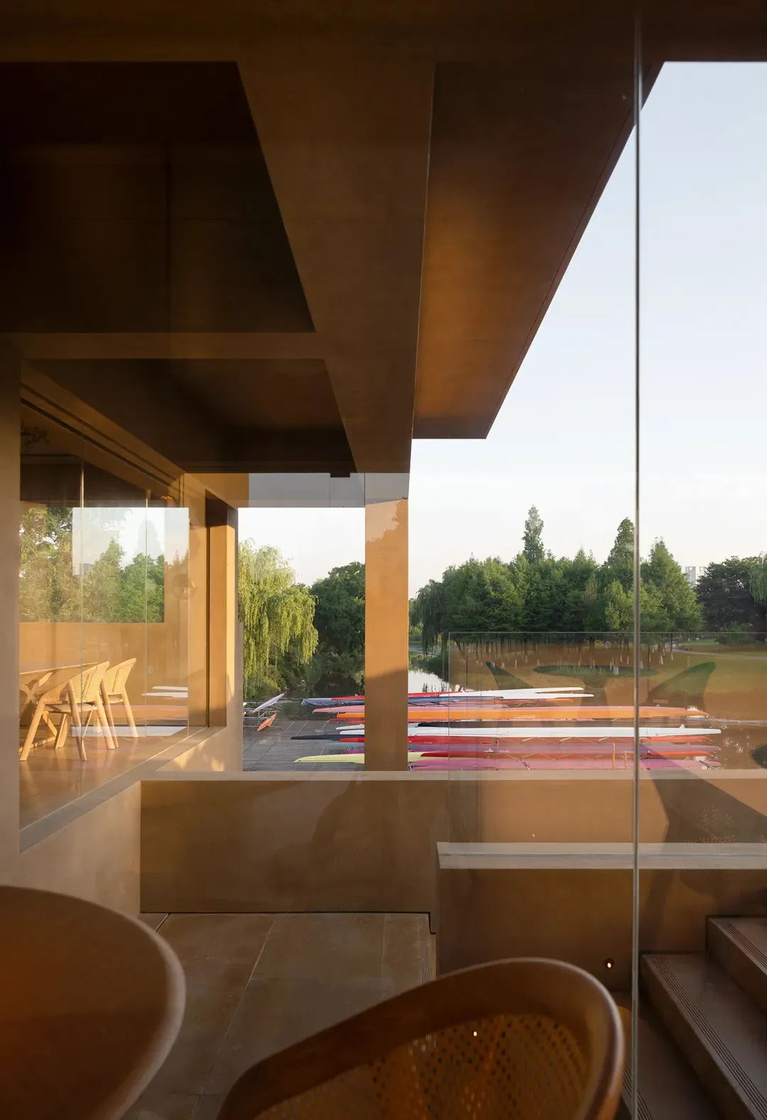 A modern interior with concrete and glass elements overlooking a terrace with boats in the water.