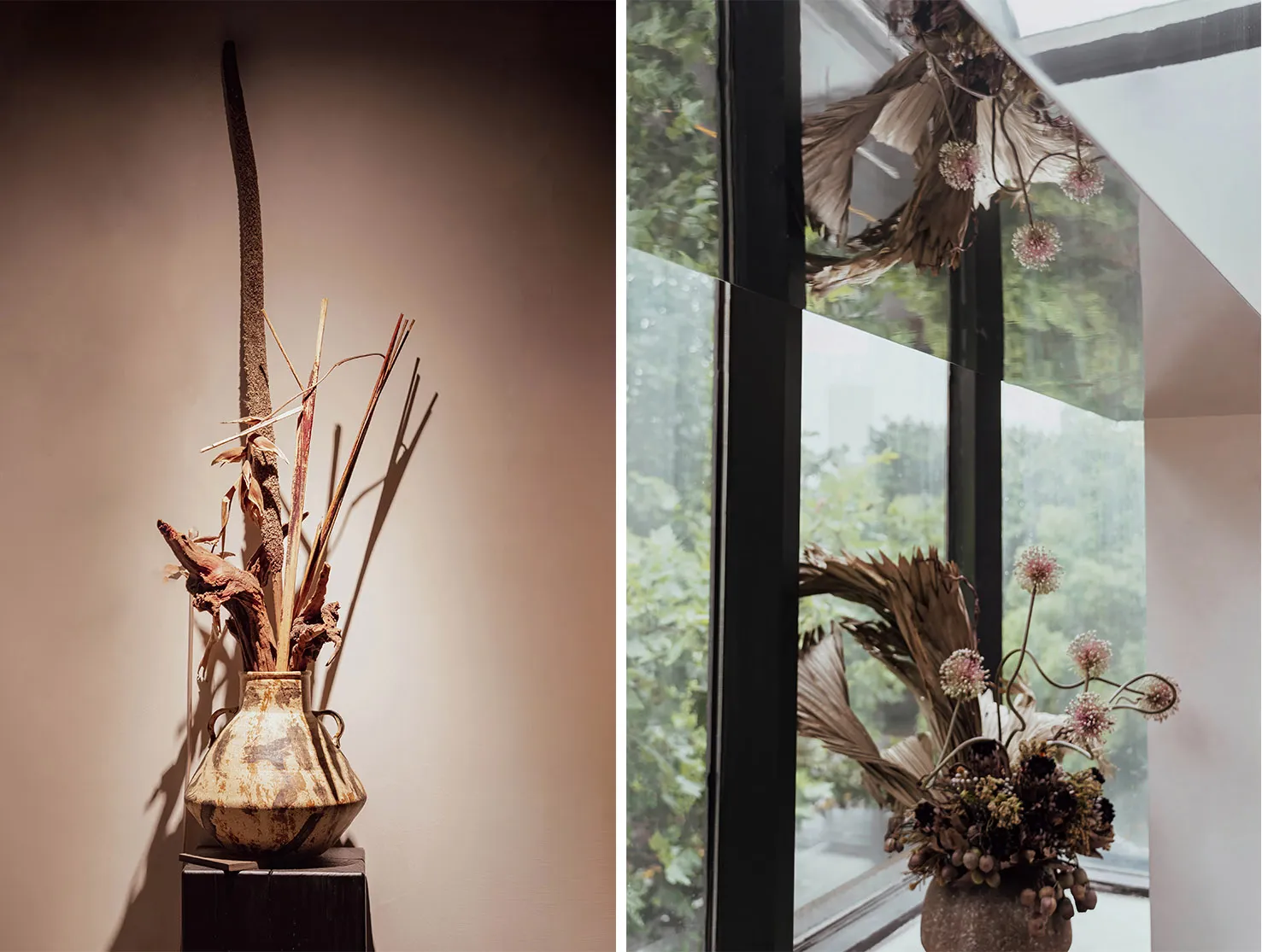 A vases adorned with dried plants sits on a wooden pedestal against a beige wall.