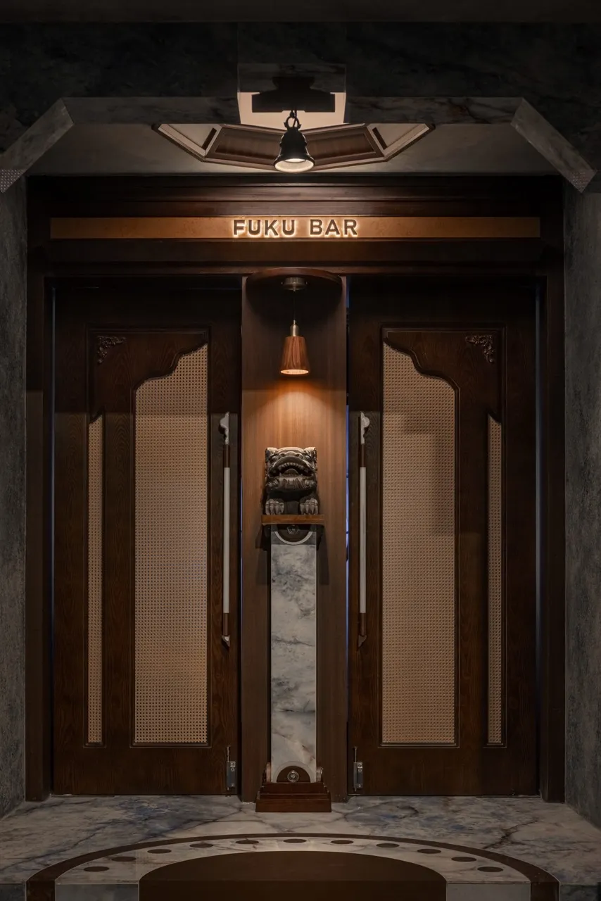 Industrial-style bar entrance with wooden doors, cane panels, and marble accents.