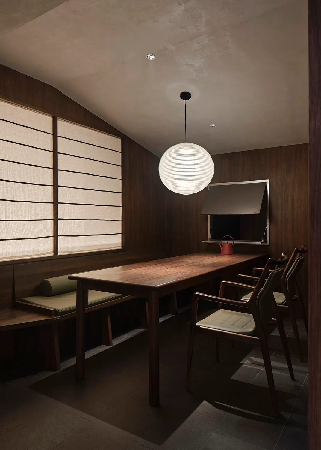 Industrial-style restaurant with a hanging ceiling lamp and wooden furniture, featuring a large window with curtains and a te