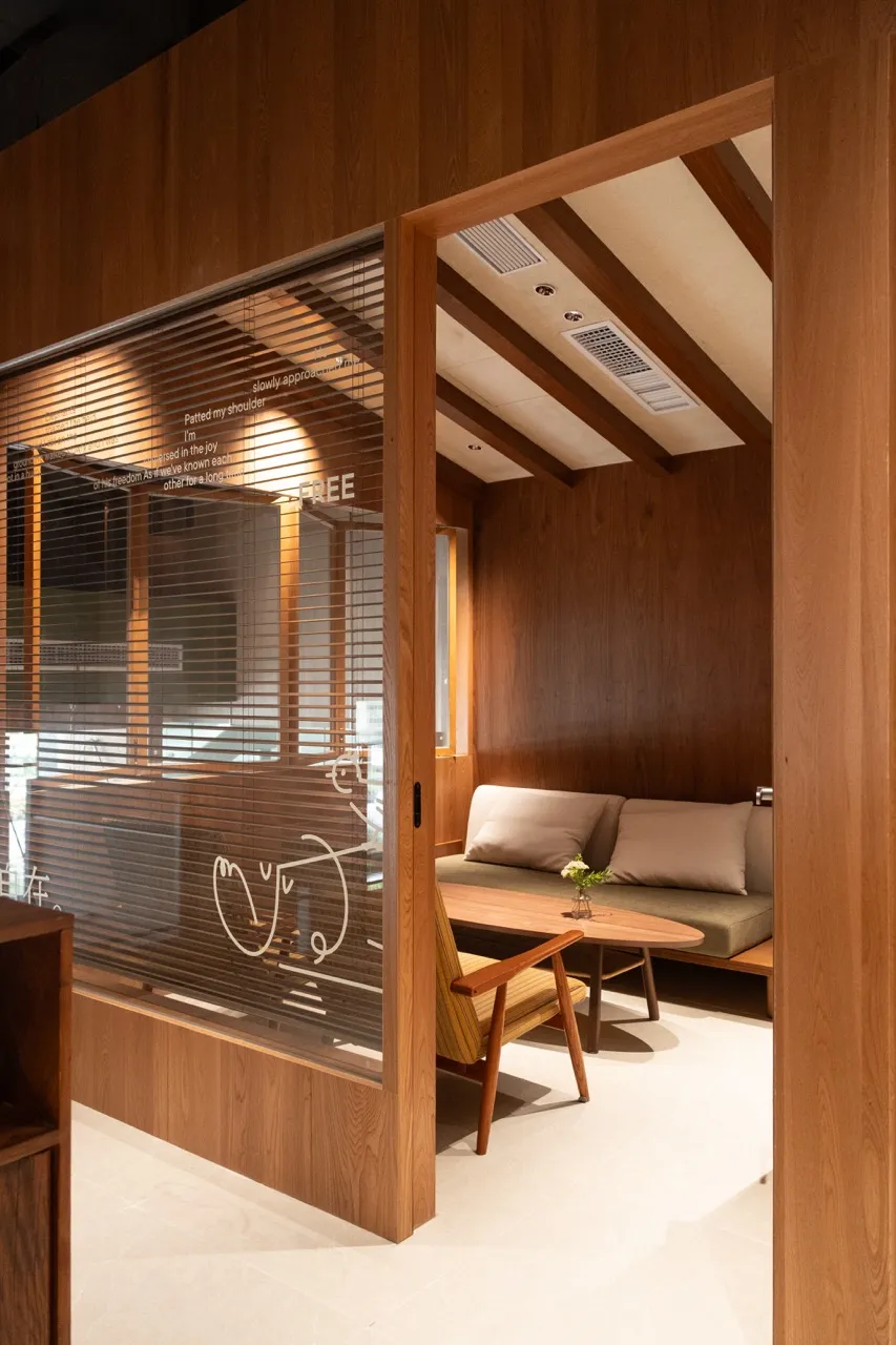 Modern, minimalist coffee shop seating area with wooden furniture and cushions.