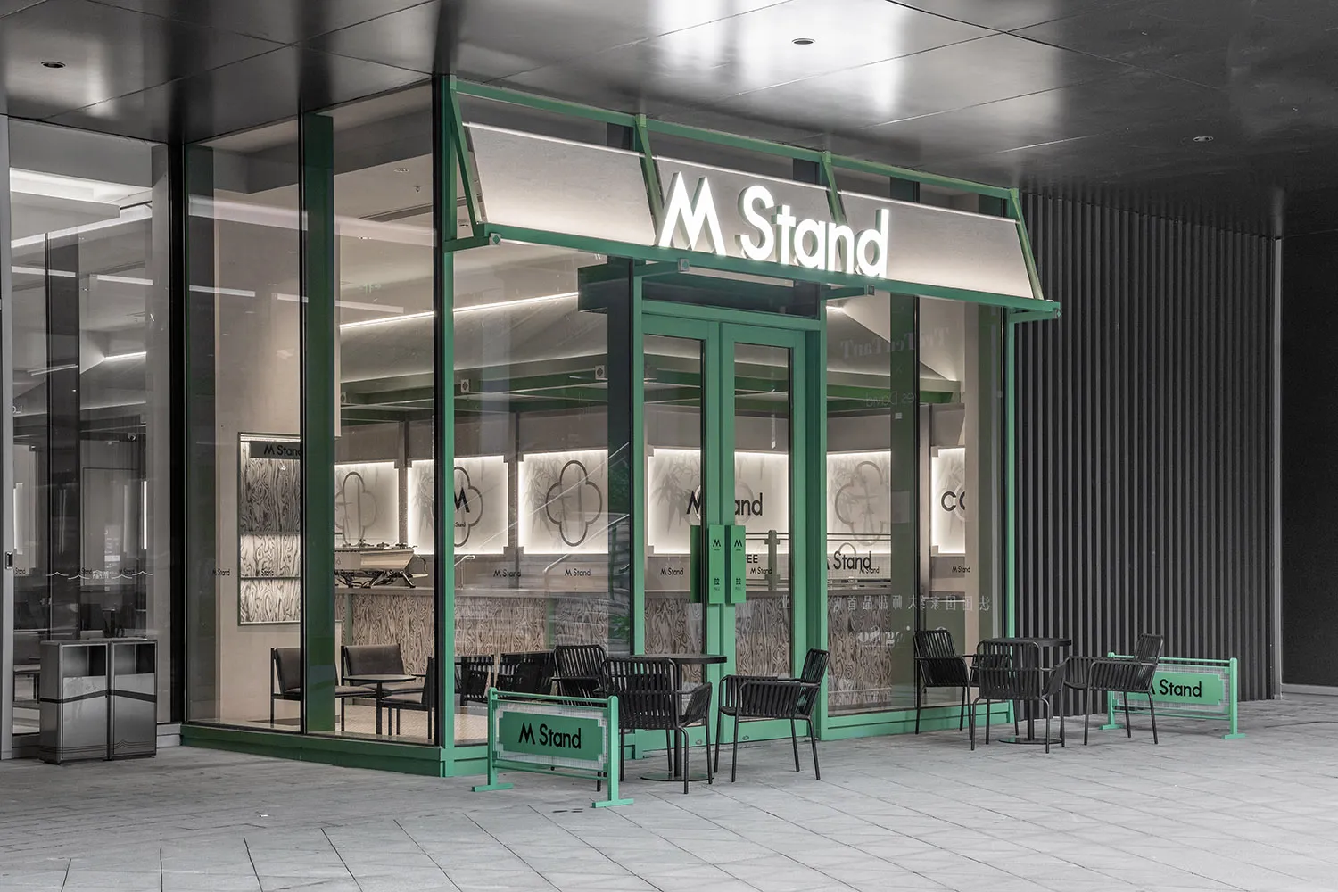 A modern retail storefront with glass walls and green accents.