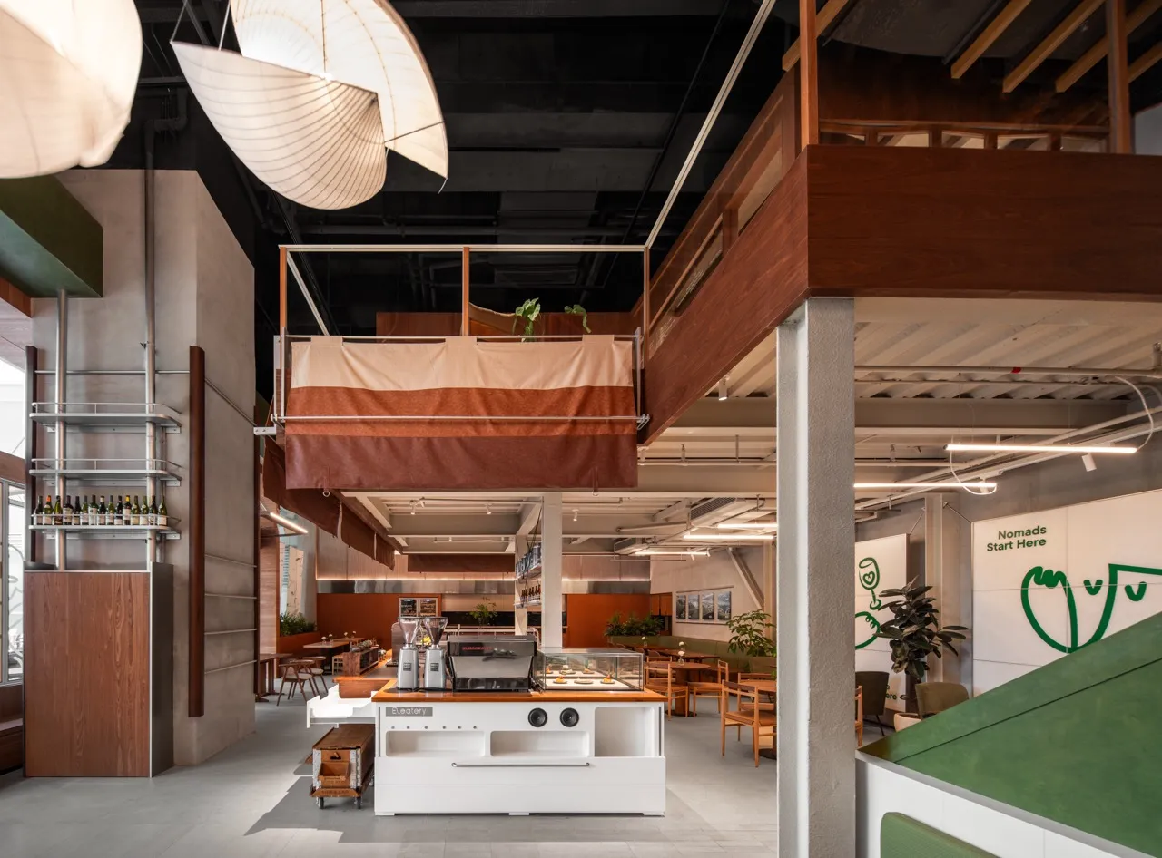 A spacious, industrial-style cafe interior featuring a wooden counter and seating area