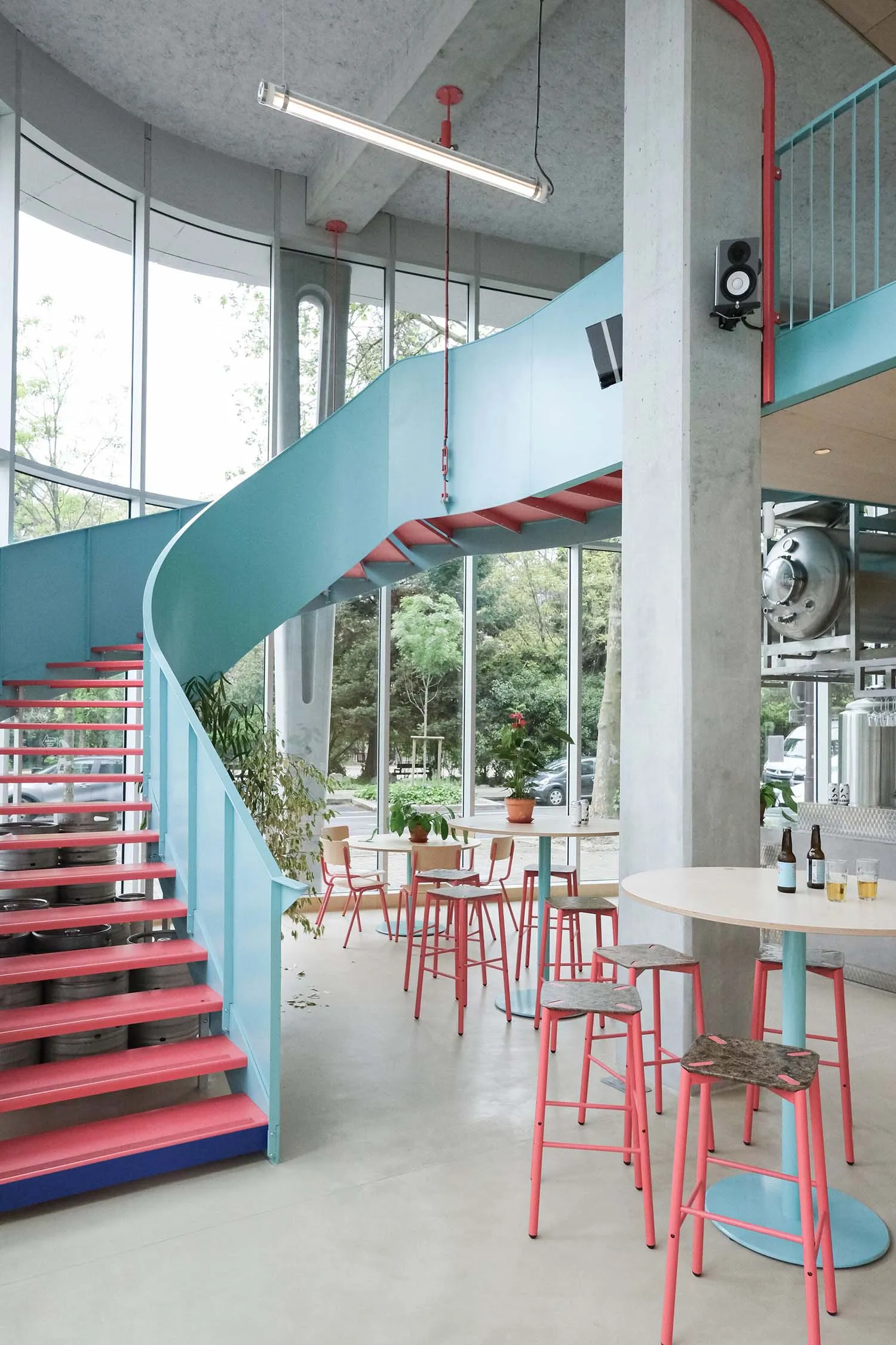 A modern, industrial-style coffee shop featuring a metal and wood staircase.