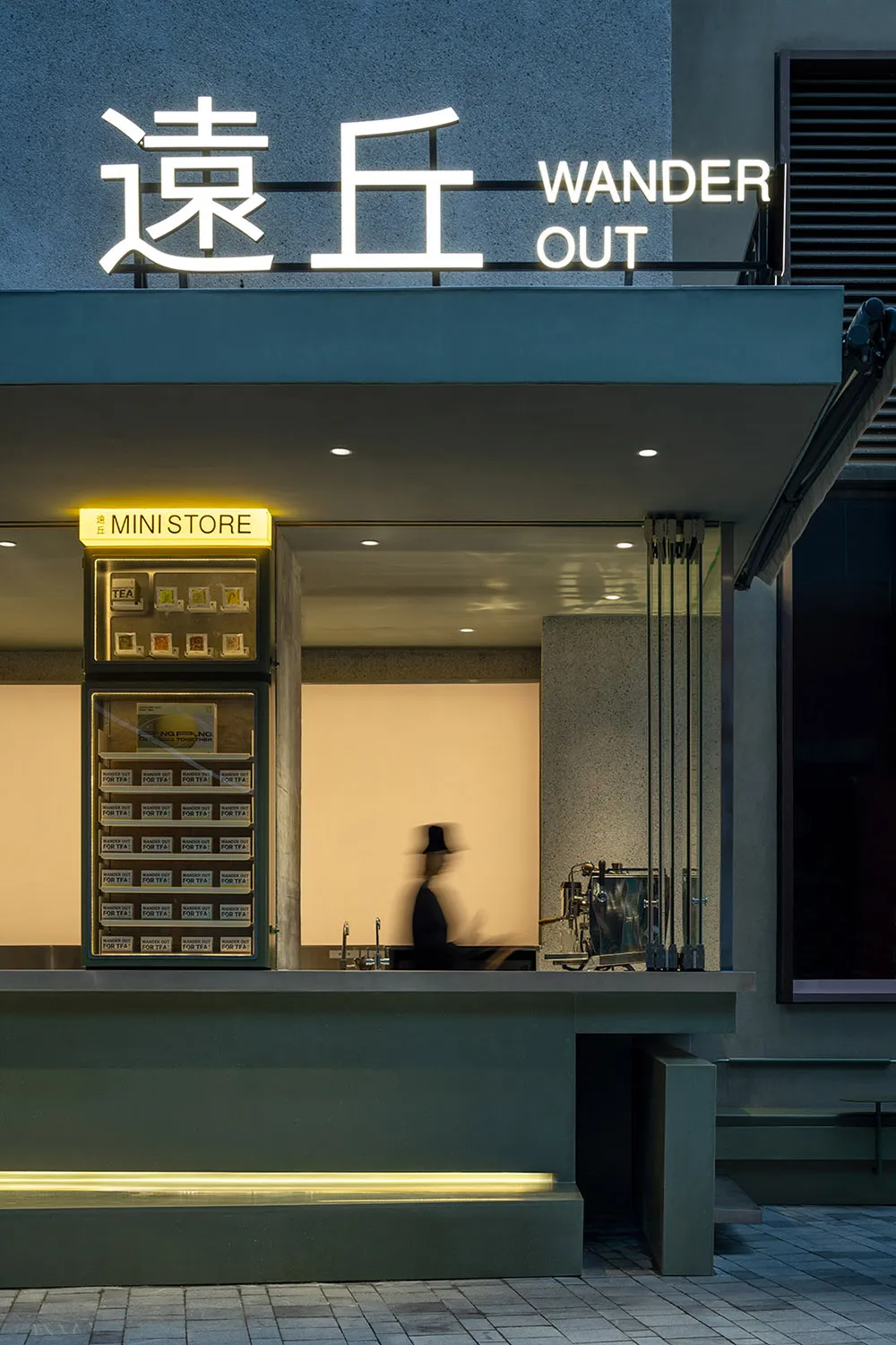 A modern retail storefront with minimalist design, featuring concrete and glass materials.