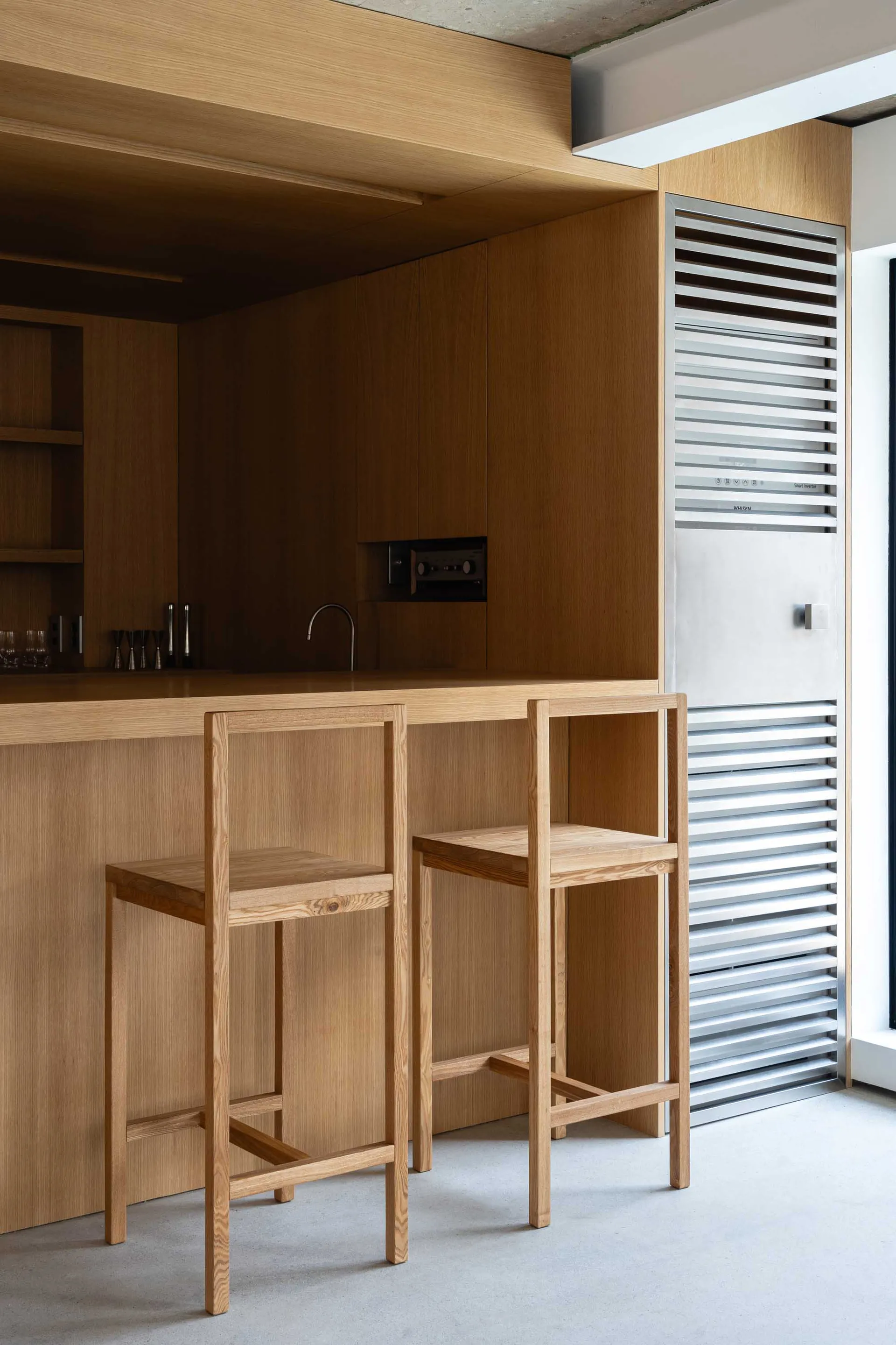 Modern minimalist kitchen with wooden cabinets and stools.