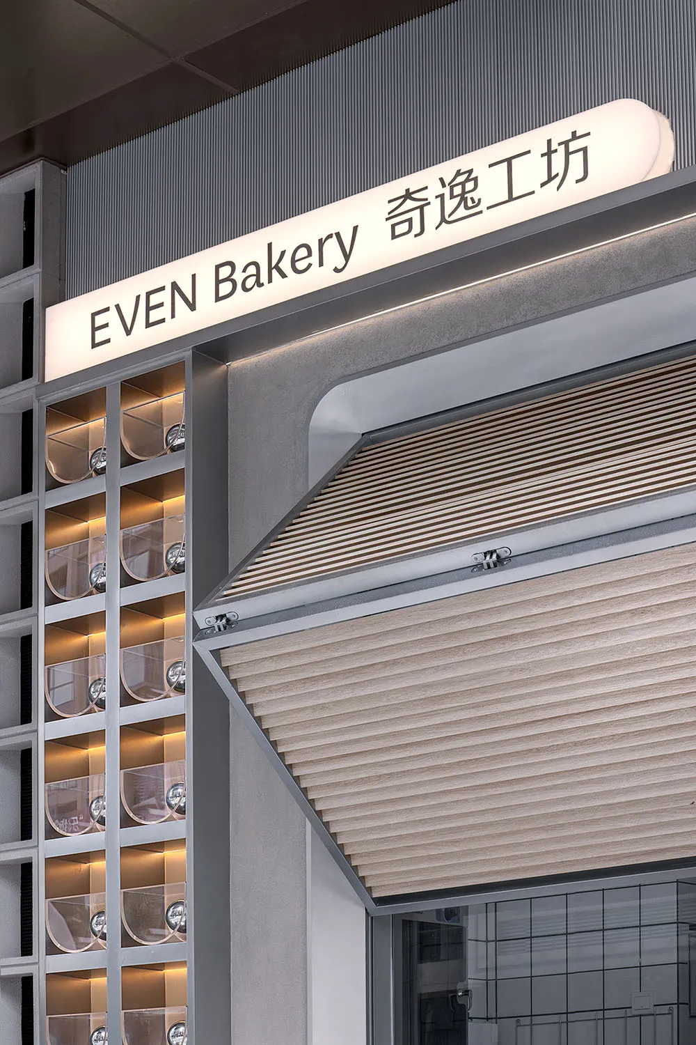 Even Bakery storefront with illuminated signage featuring metallic elements.