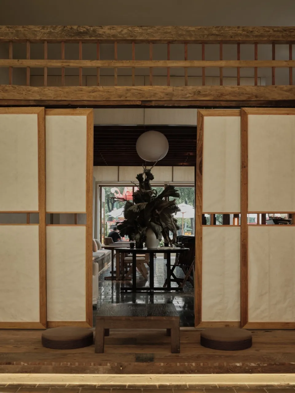 A traditional Japanese restaurant interior with paper walls, wooden beams, and a decorative plant on a round table.