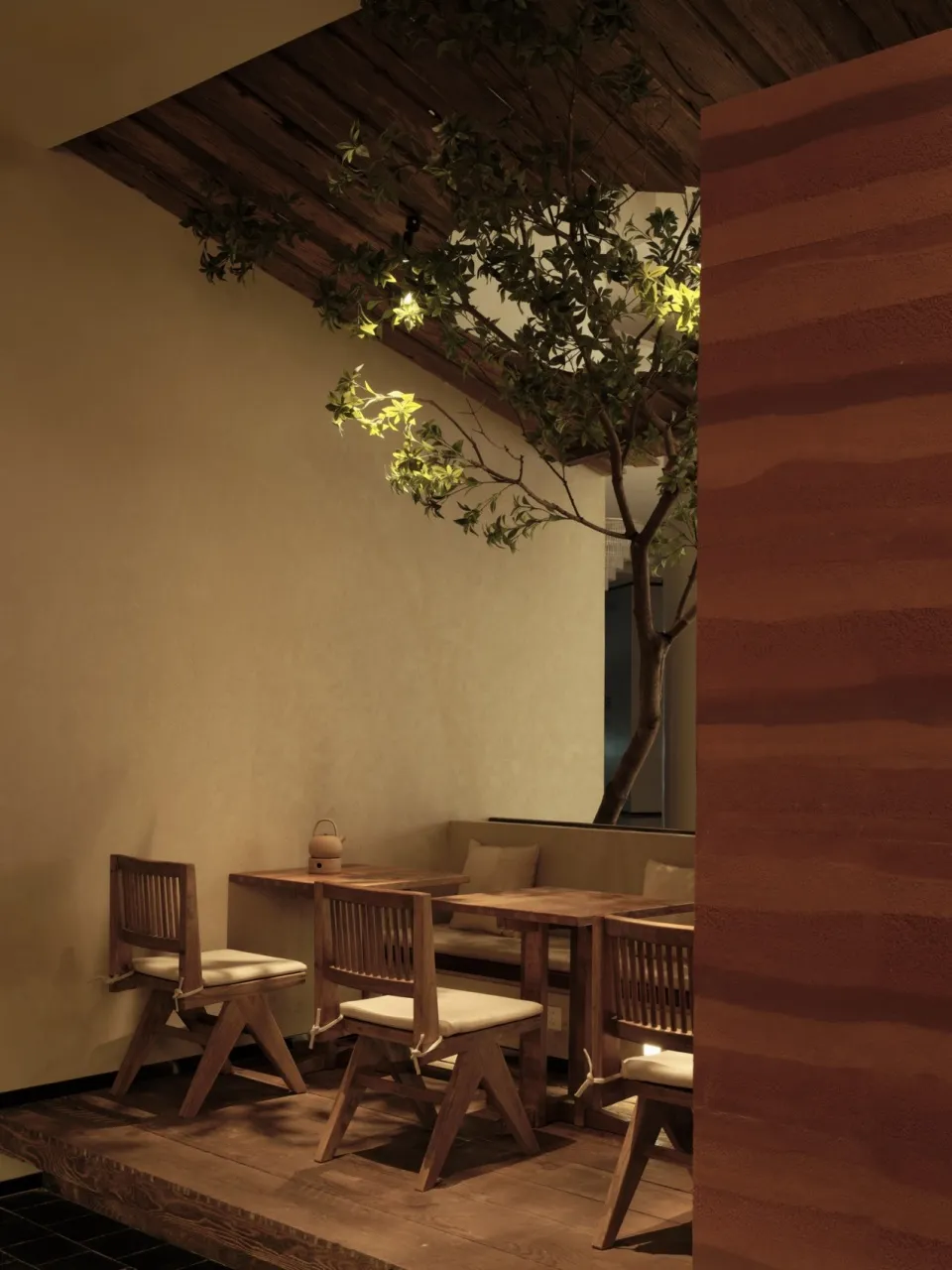 A minimalist restaurant interior featuring wooden furniture and a plant.