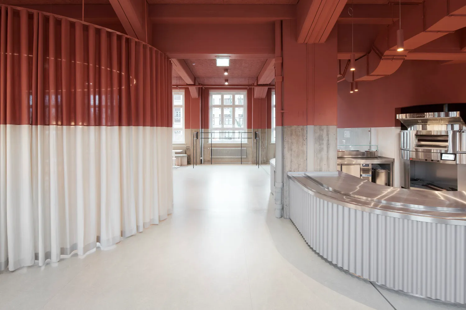 Modern cafeteria interior with red and white curtains, white flooring, and industrial-style materials.