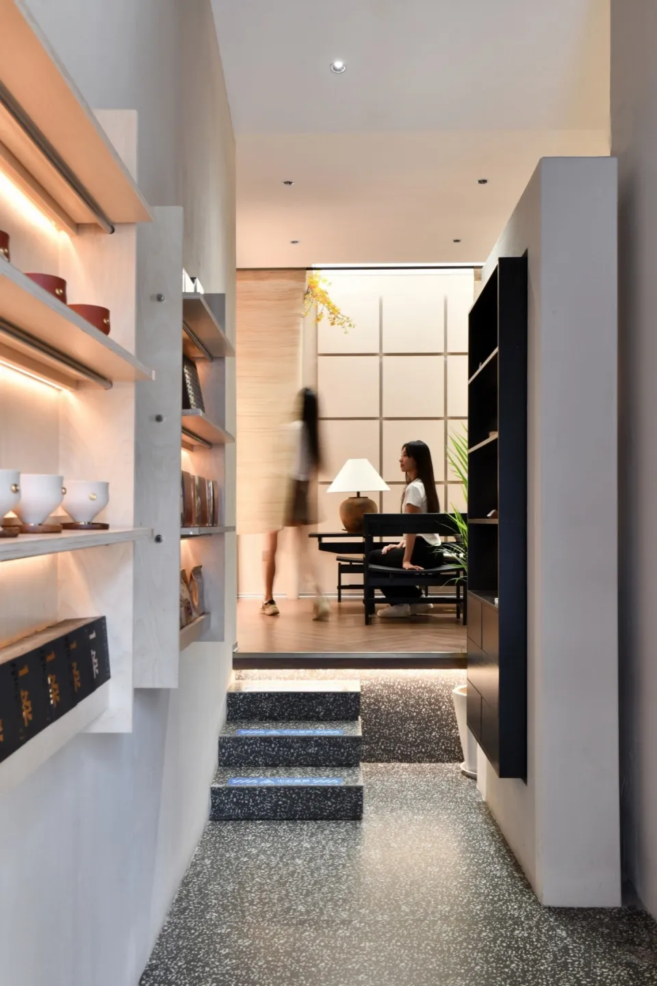 Modern entrance hall with concrete and terrazzo flooring, featuring minimalist design and natural lighting.