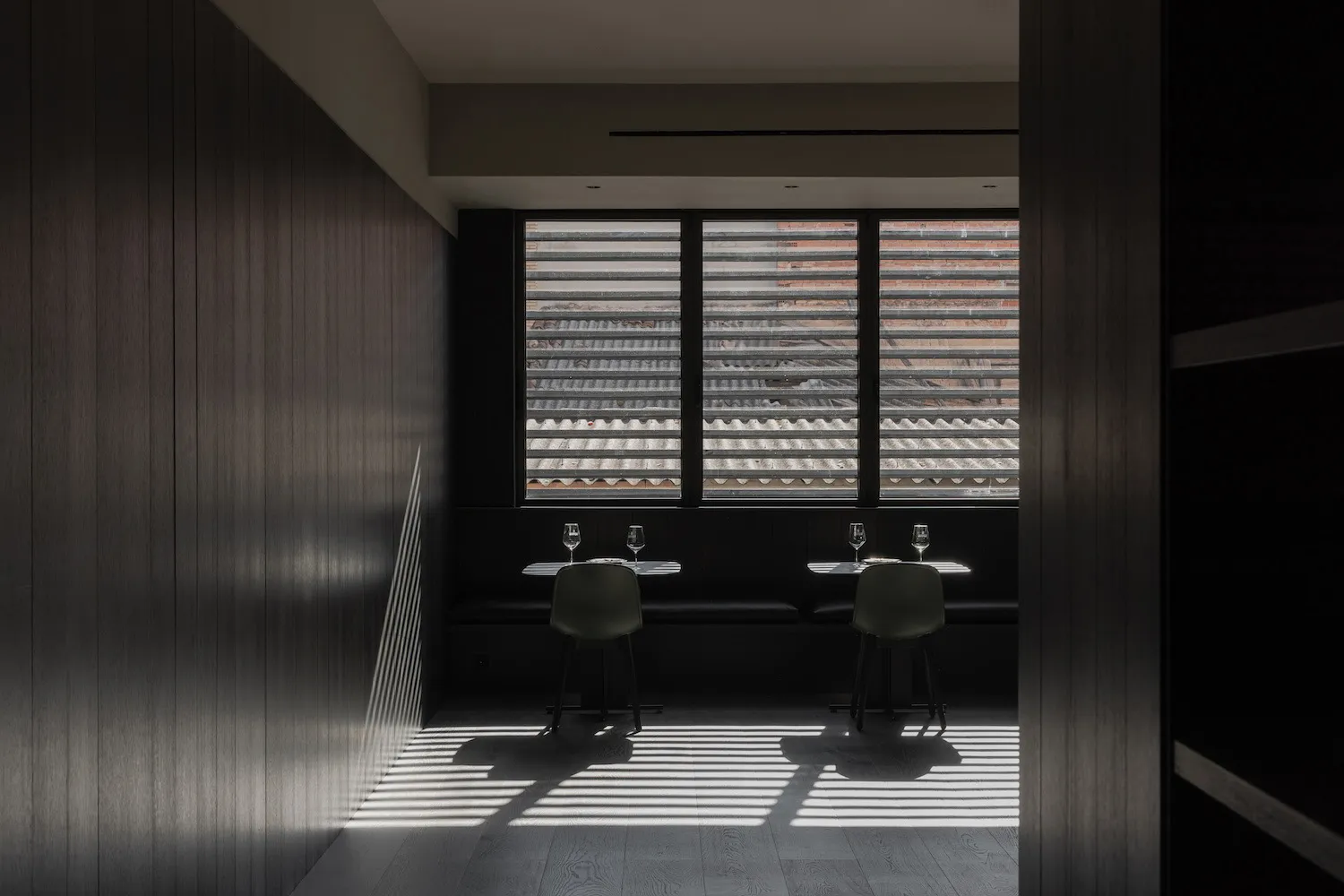 Interior of a modern restaurant with dark accents, featuring minimalist design and wooden materials.