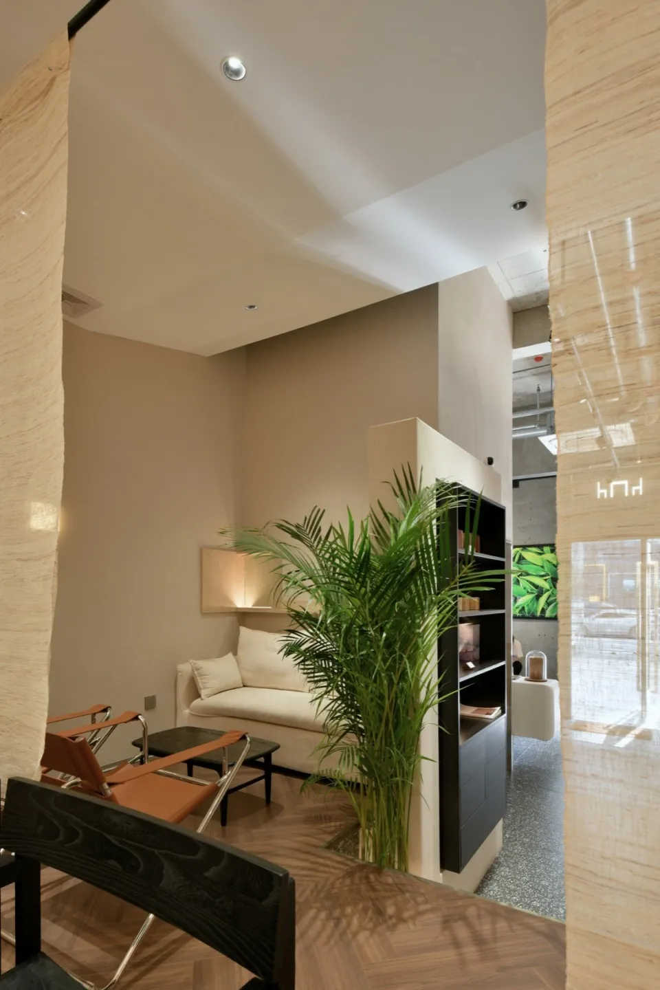 A minimalist living room with concrete walls, a white sofa, and a potted plant.