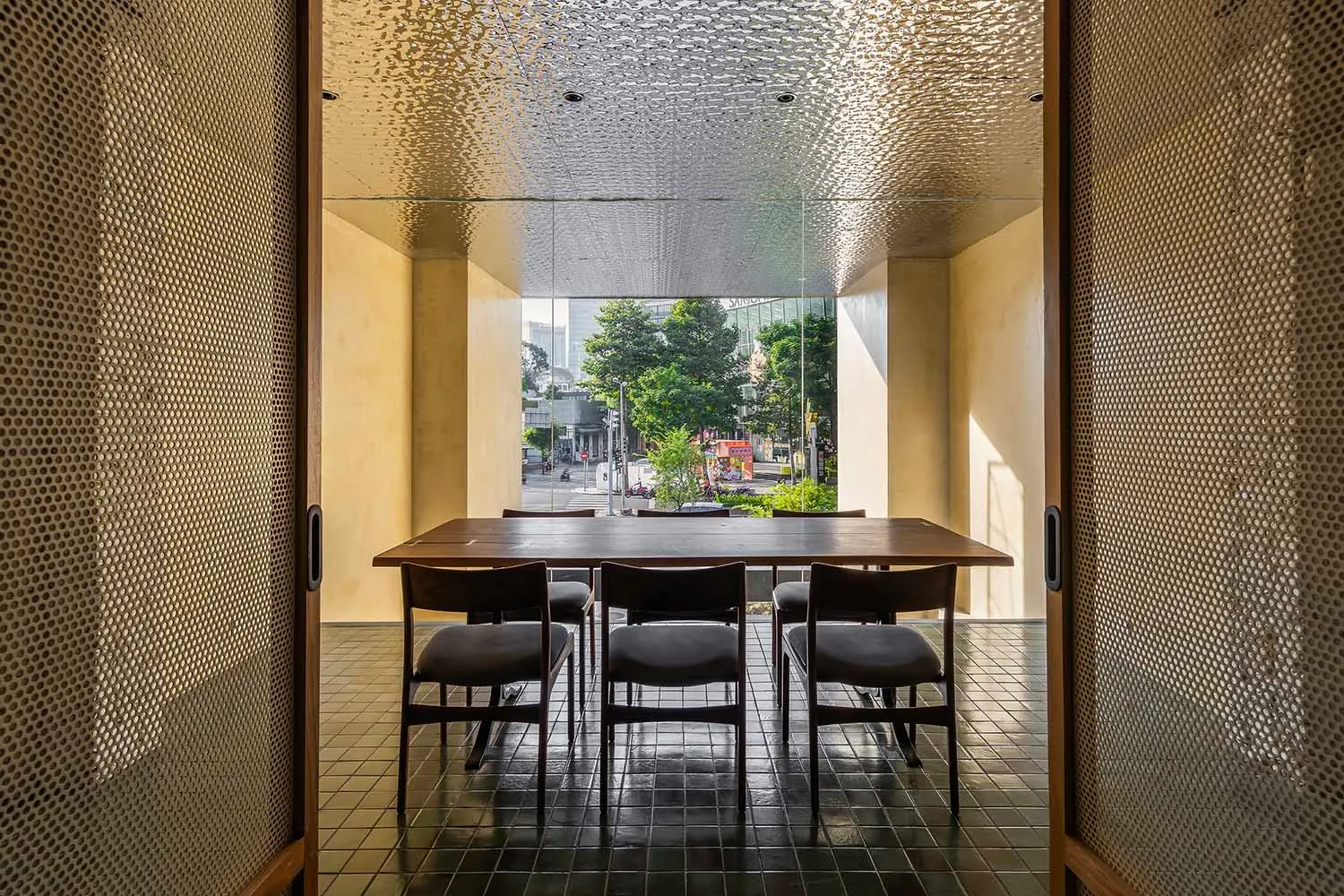 現代餐廳內擺放木質餐桌與餐椅,桌椅前方為大型窗戶,可眺望都市街景。