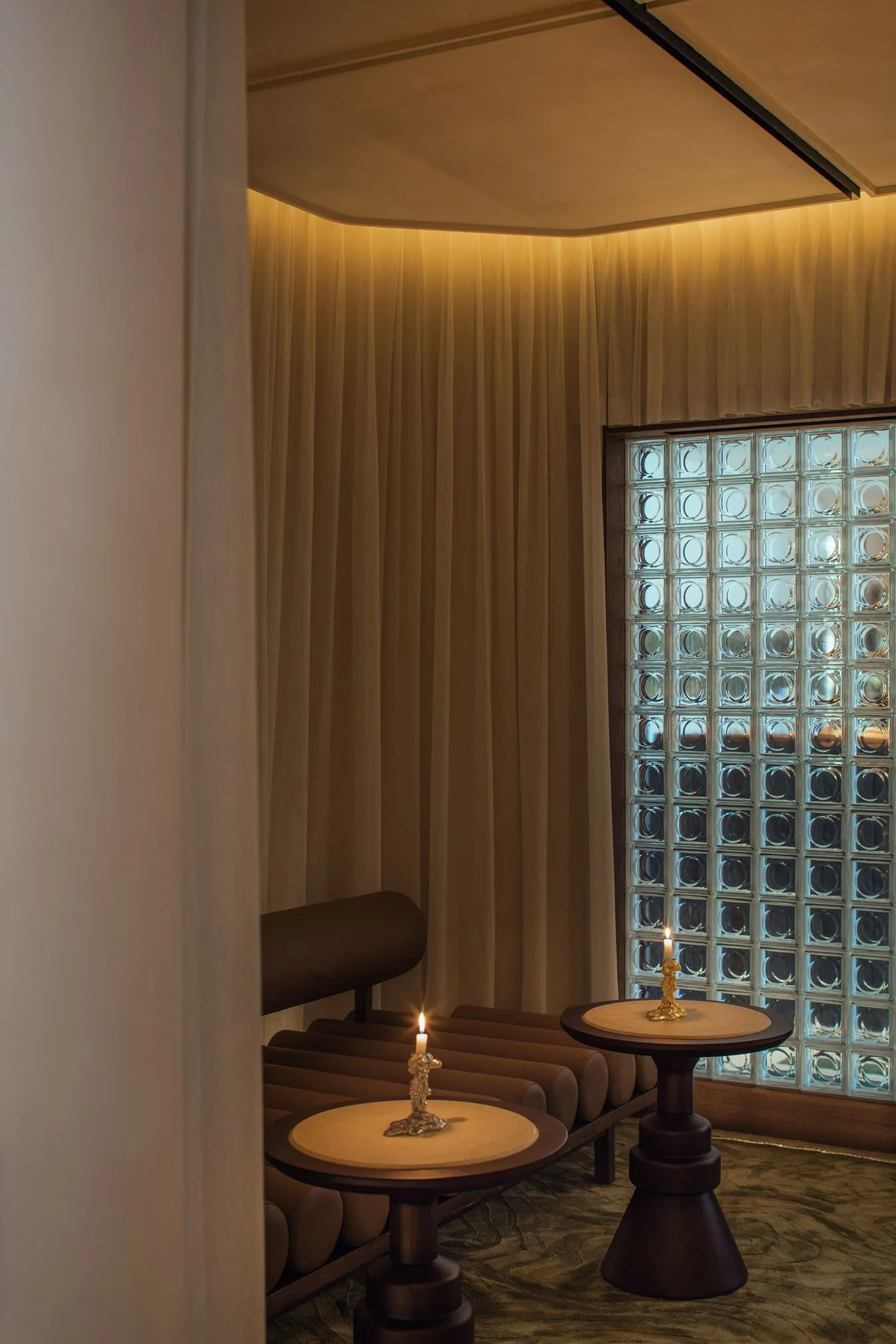 A serene spa relaxation room featuring glass blocks and soft curtains.
