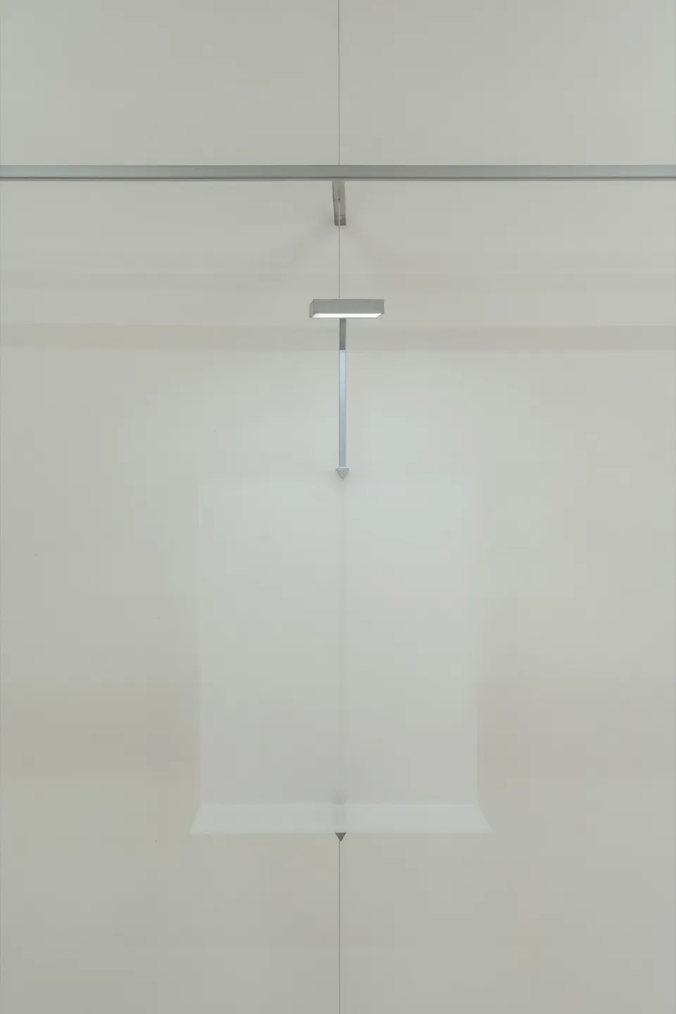 A minimalist glass floating object installation art piece mounted on a white wall.