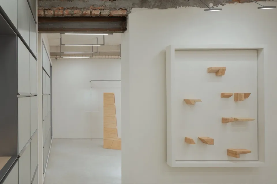 A minimalist office space with wooden columns, white walls, and an industrial ceiling beam.