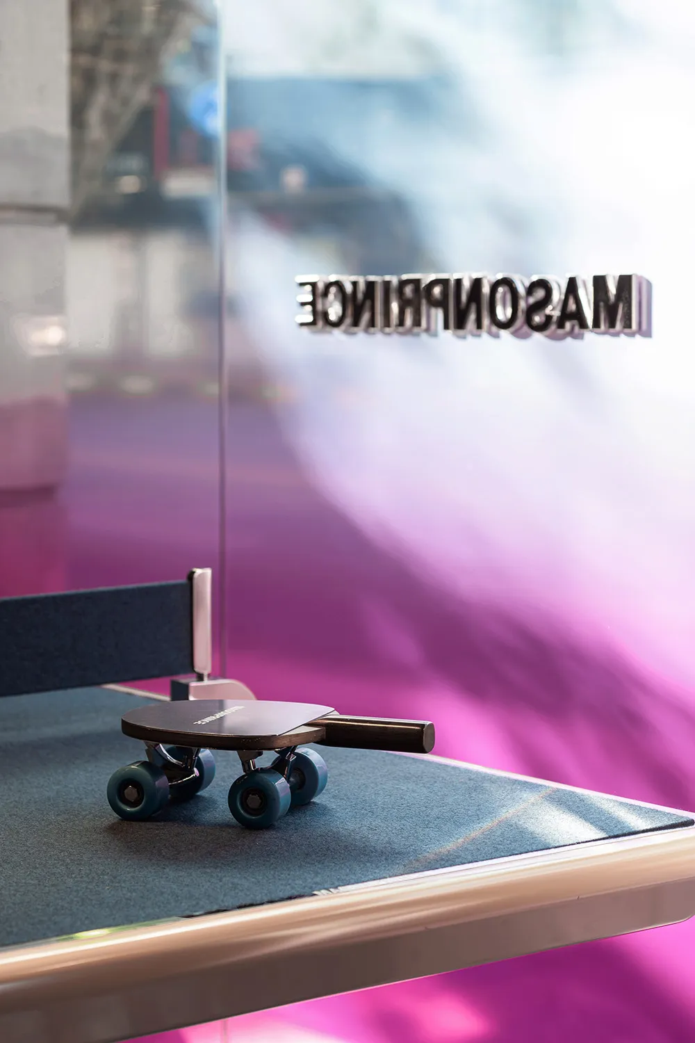 A table tennis paddle attached to a skateboard, suggesting a playful fusion of table tennis and skateboarding