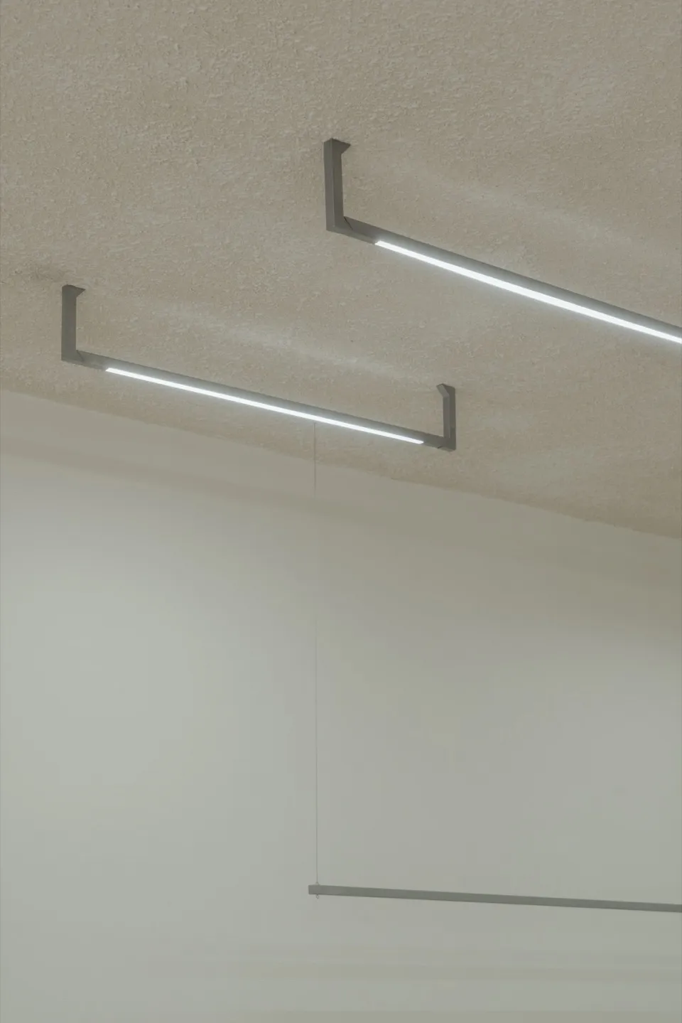 A modern interior space featuring concrete walls and minimalist lighting fixtures.