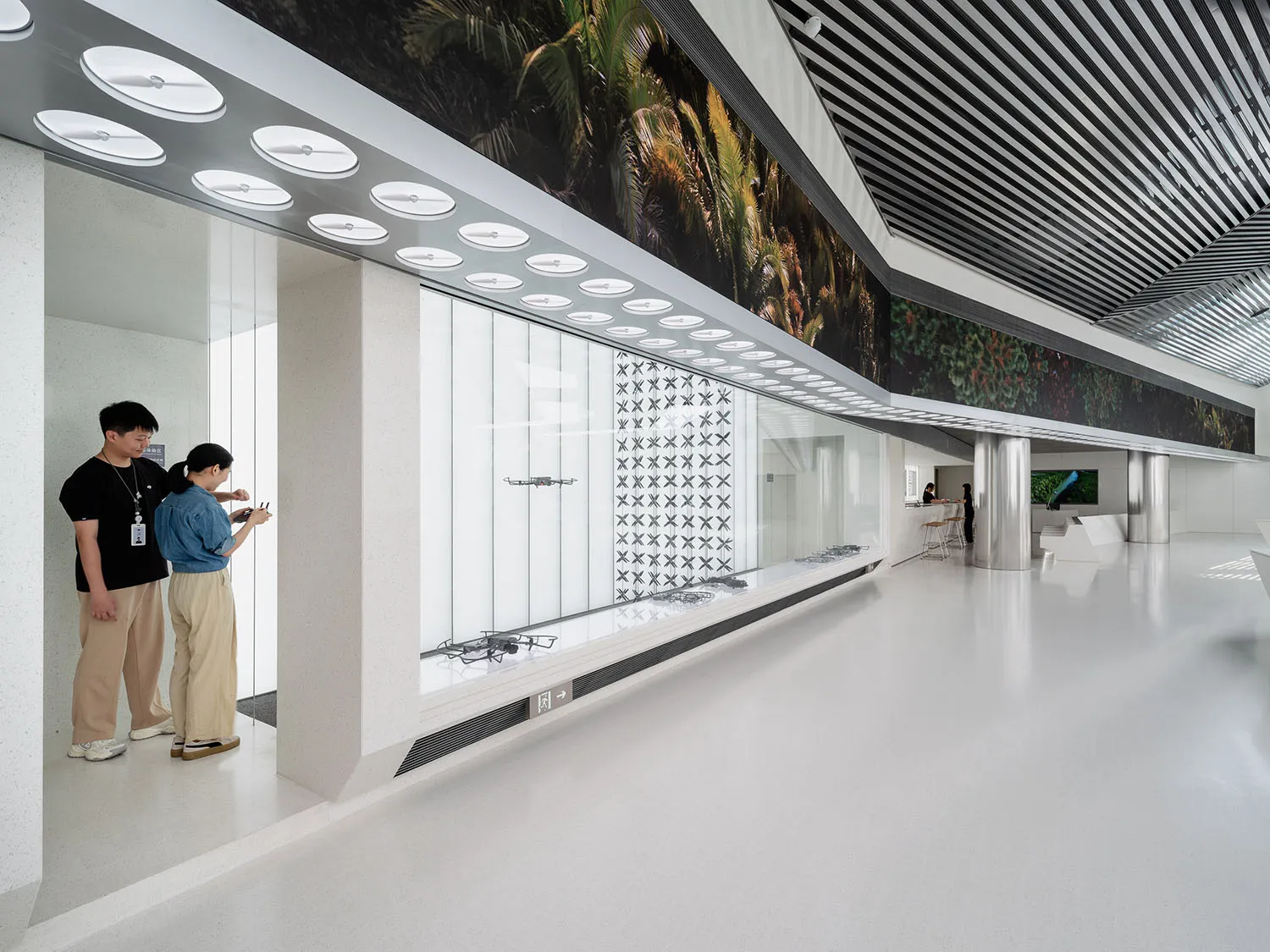 People operating drones indoors in a modern office setting with glass walls and metal accents.