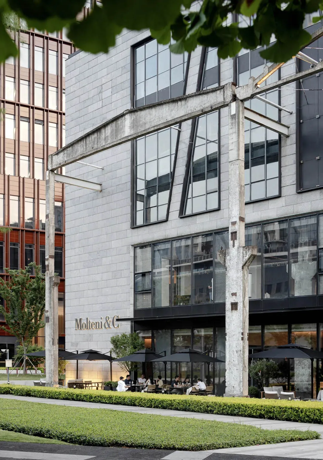 Modern restaurant exterior with concrete facade and large glass windows.