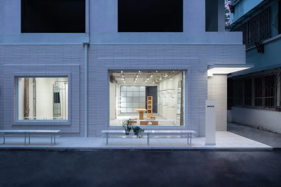 A modern retail storefront with brick exterior and white accents, featuring large windows and a minimalist design.