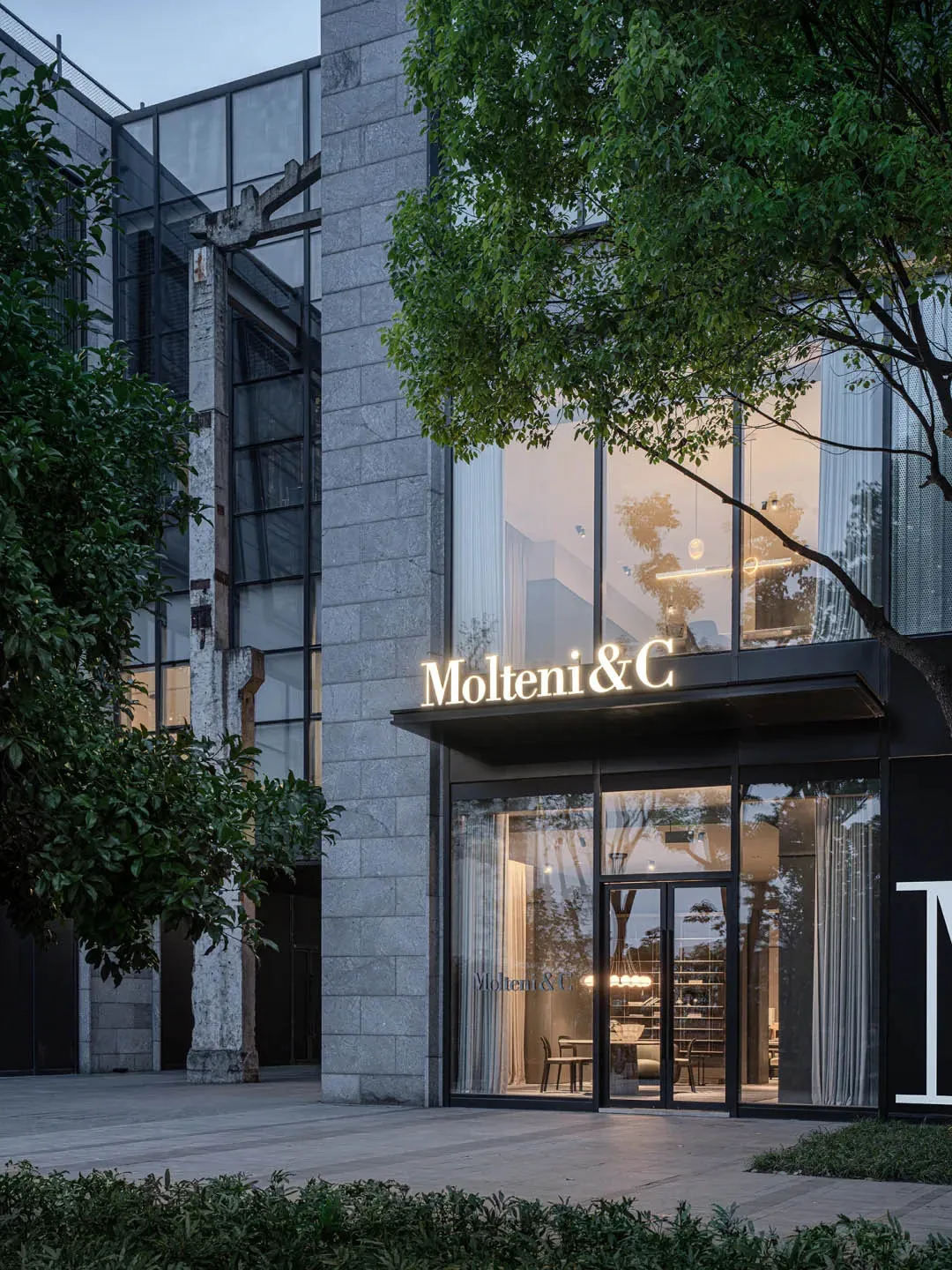Modern storefront featuring glass, concrete, and lighting elements.