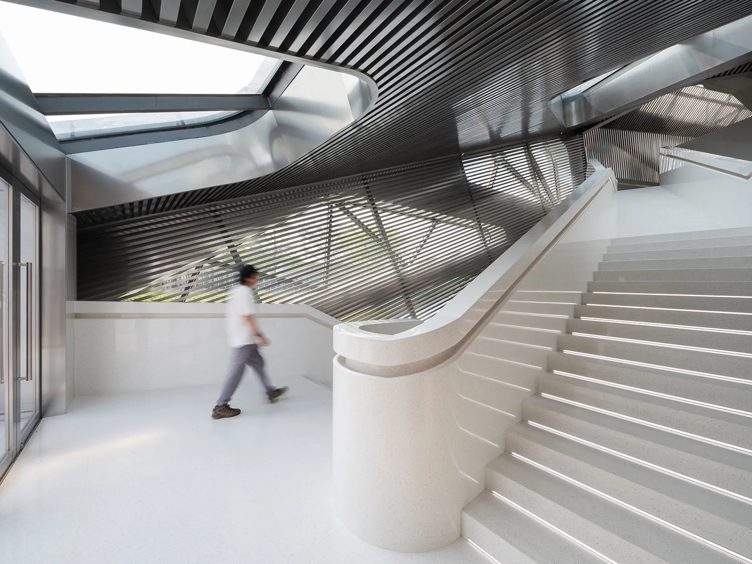 Modern concrete staircase with a white surface and a geometric ceiling design.