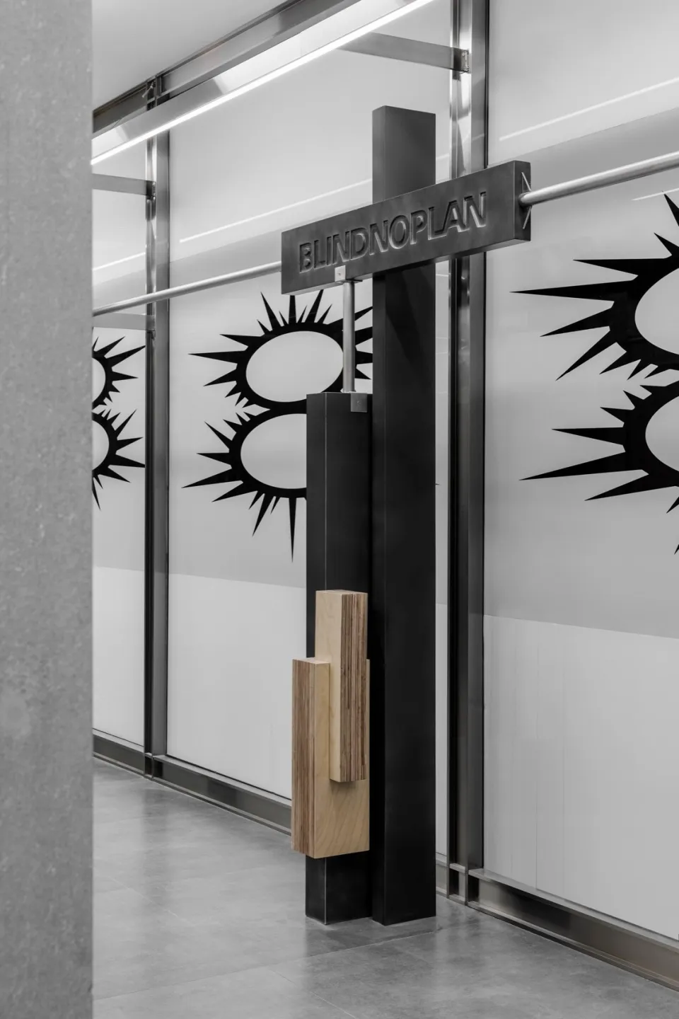 Modern minimalist interior design featuring a black-framed glass entryway with an abstract logo design.