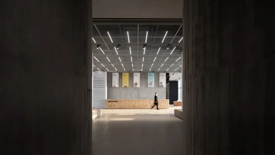 A modern industrial-style lobby with concrete walls and floors, featuring a minimalist design and contemporary lighting fixtu