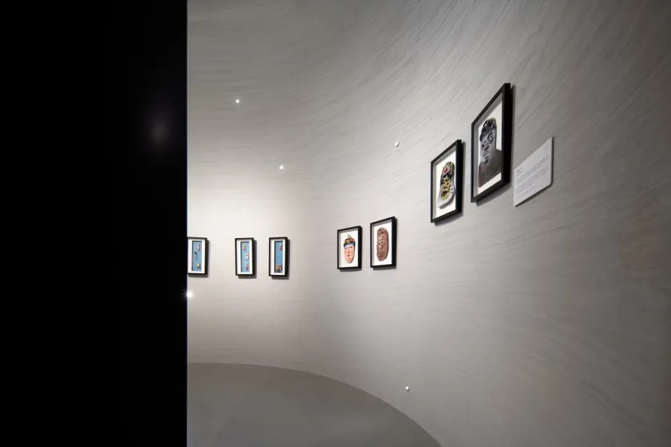 一間畫廊空間,藝術作品陳列在弧形白瓷磚牆上。