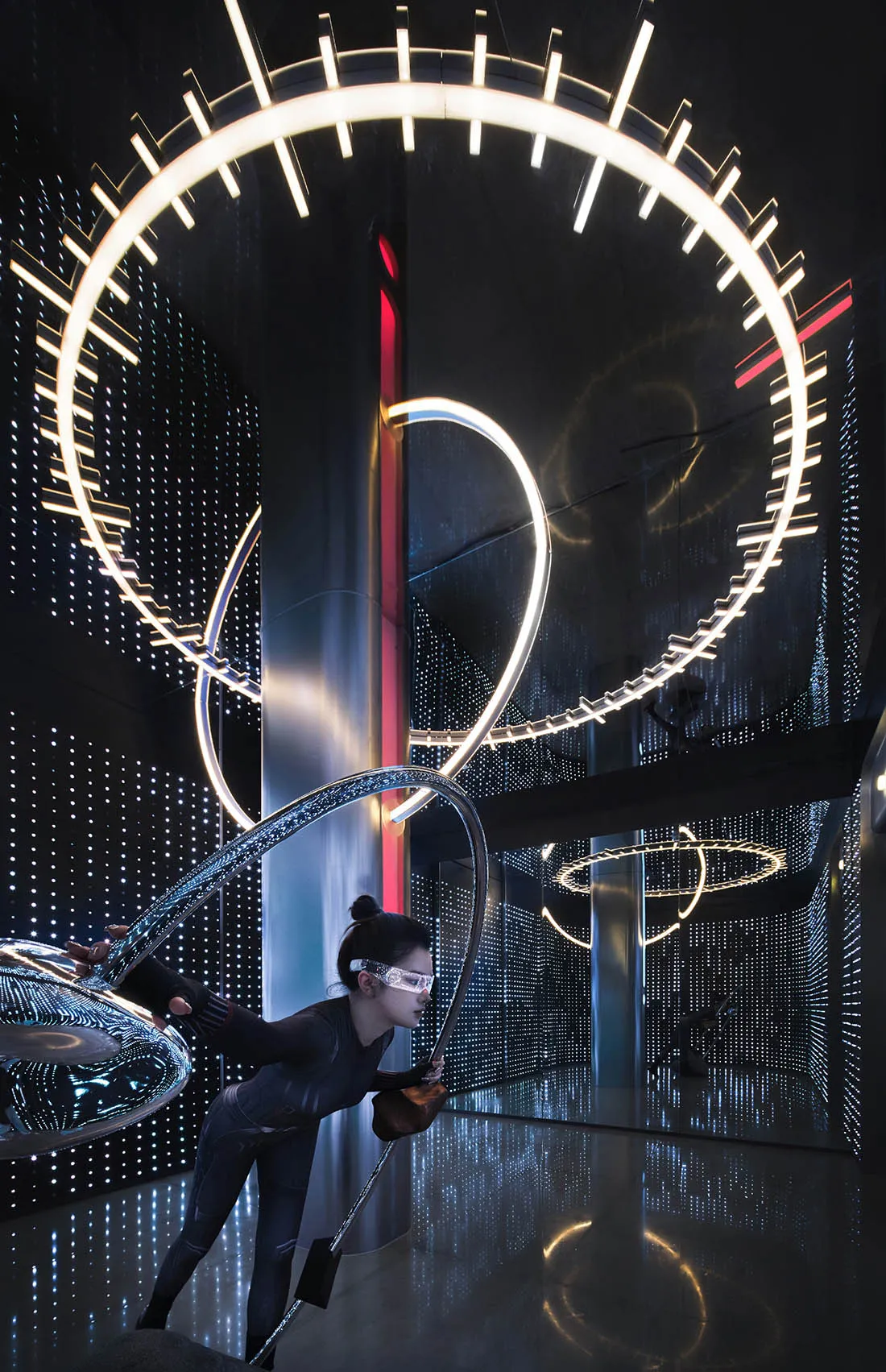 A person performing in a modern artistic space with metallic elements and circular light fixtures.