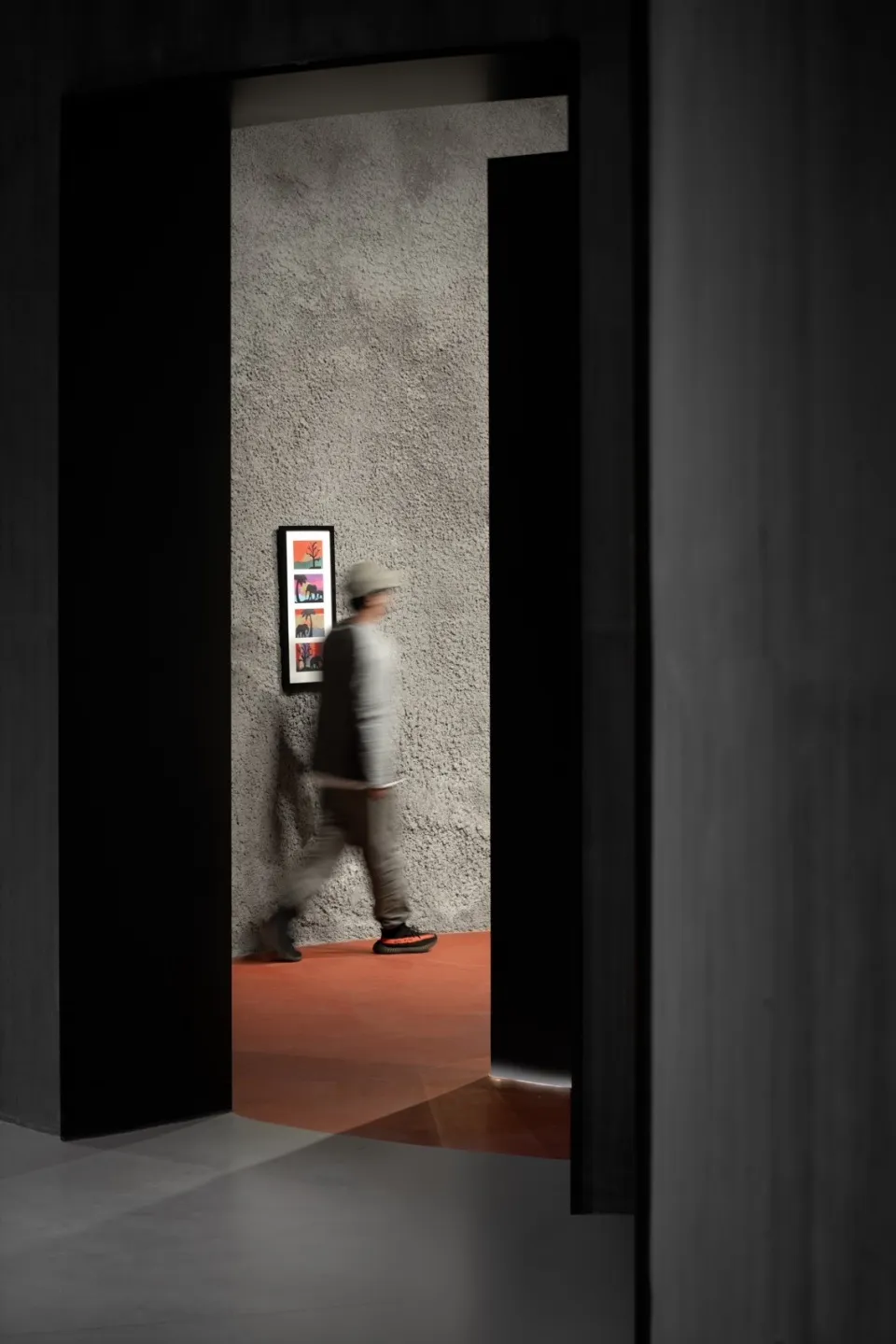 A modern interior with concrete walls and a person walking in a hallway.