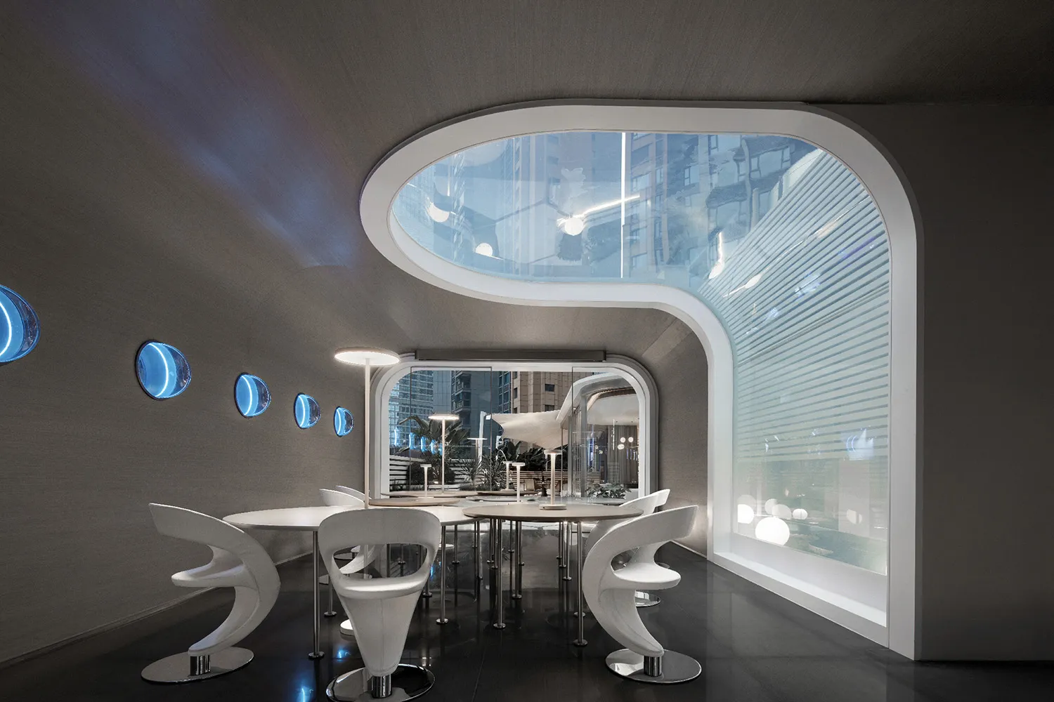 A modern restaurant with glass walls and visible cityscape through the windows.