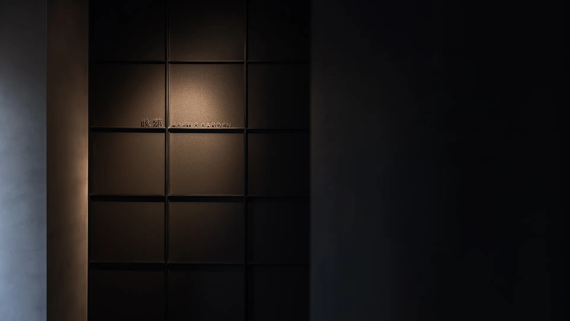 A minimalist interior with a dark metal grid wall