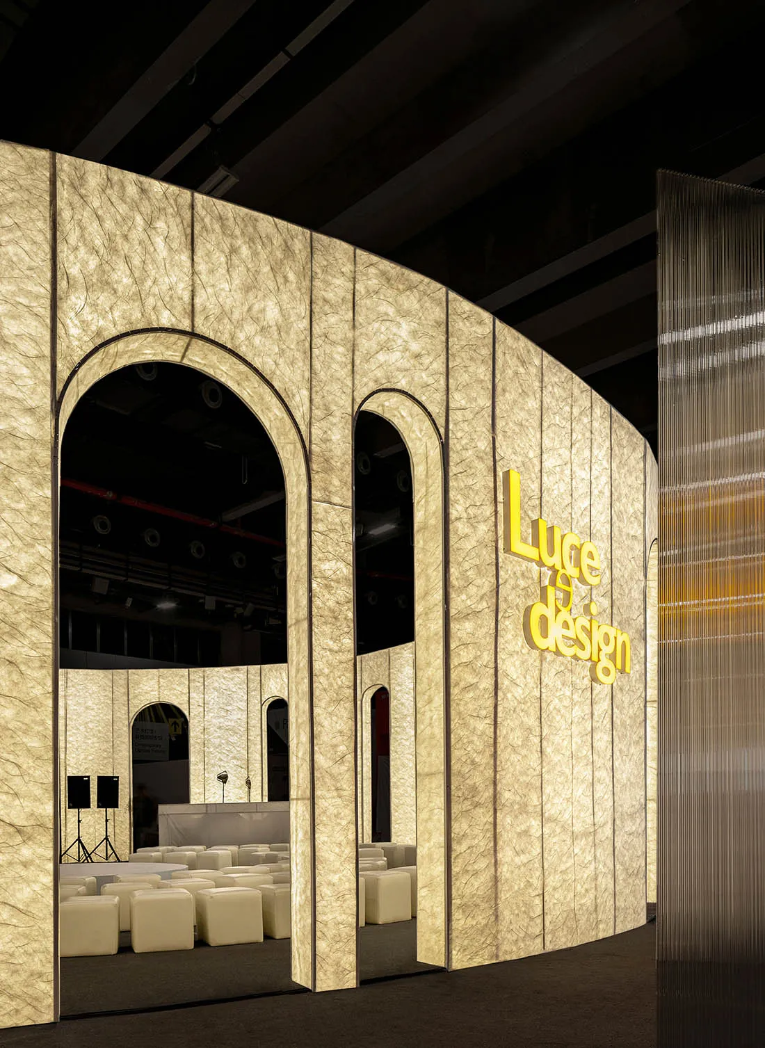 A curved, illuminated paper partition with lighting systems within the event space
