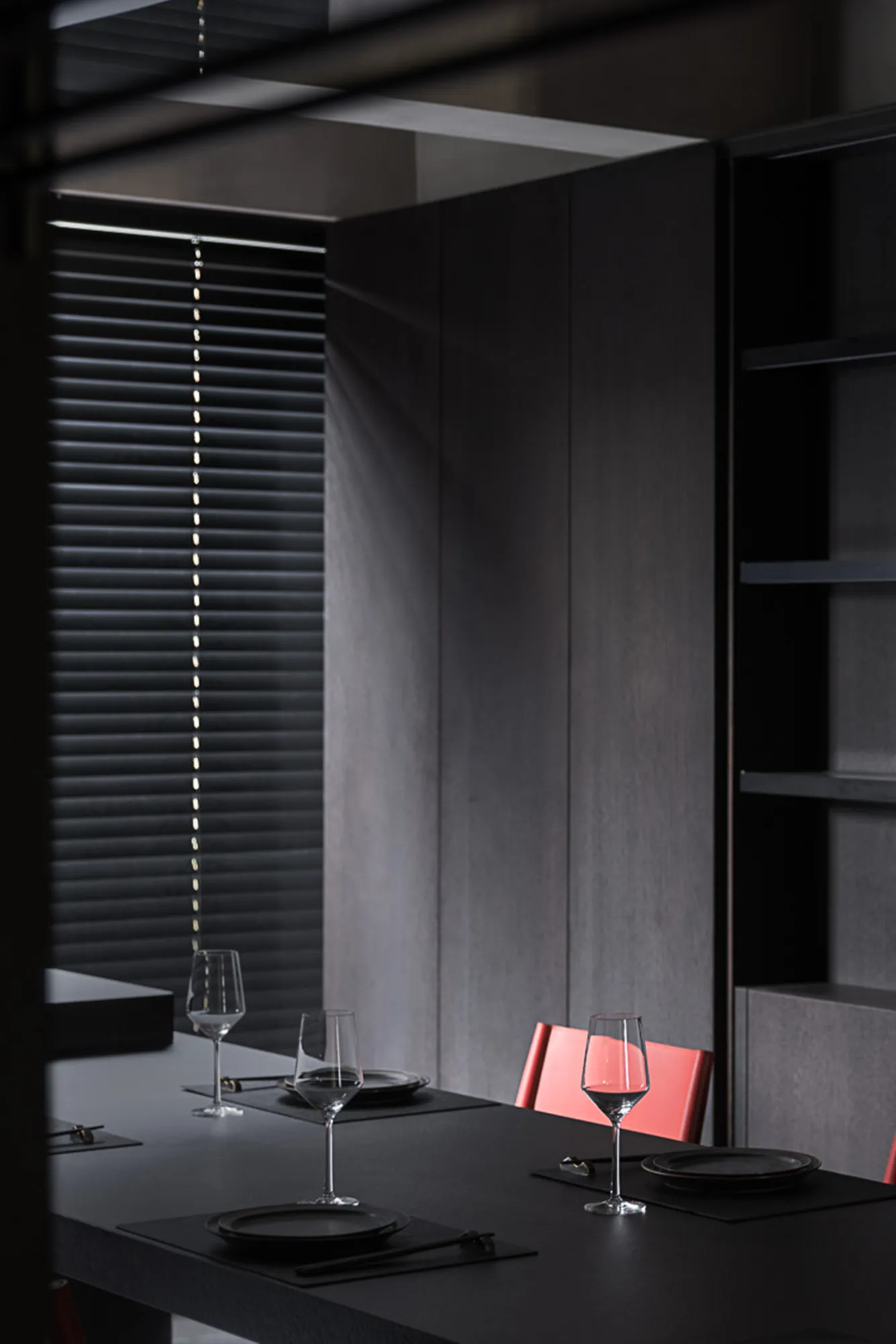 A minimalist dining room with black walls and furniture, showcasing sleek design and contemporary style.