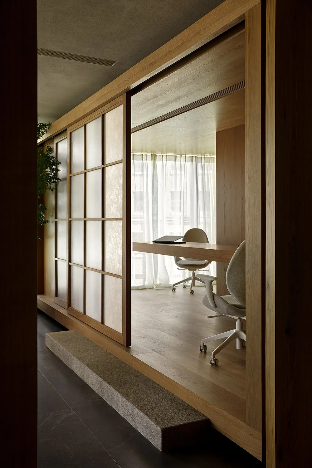 An office space with minimalist design, paper walls, and wooden furniture.