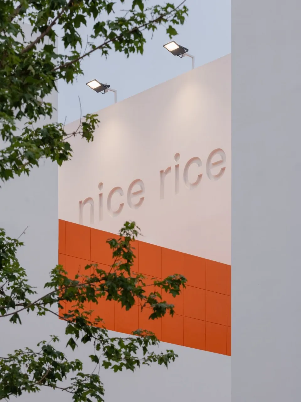 Modern, minimalist restaurant exterior featuring concrete and bright orange tiled accents.