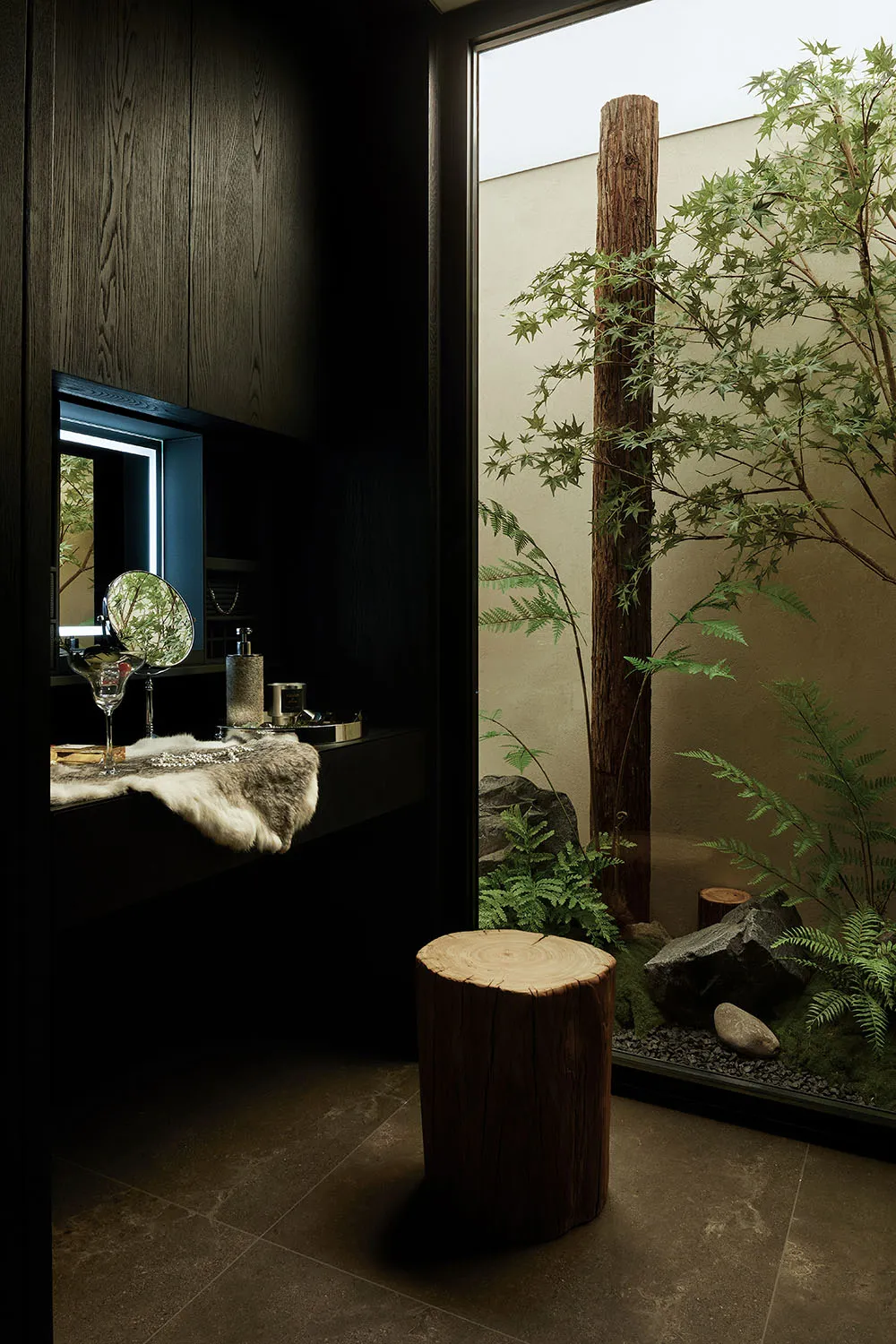 A modern bathroom featuring a wooden bench next to a glass wall with a tree and rocks inside.
