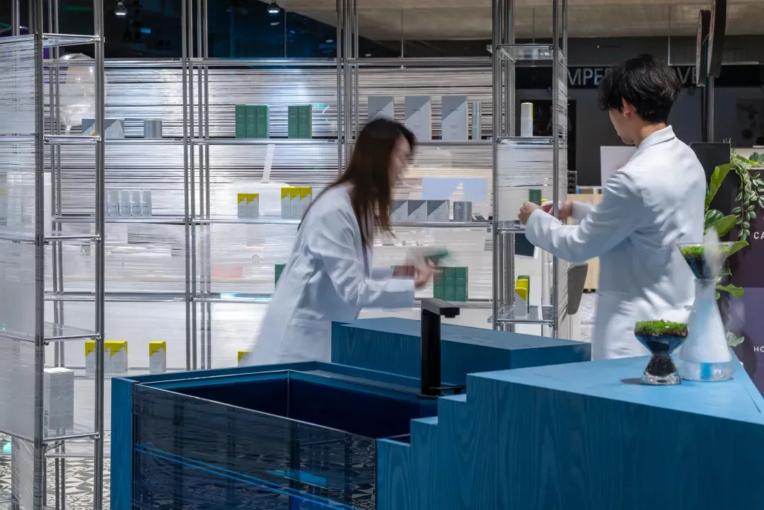 Two people in white lab coats working in a modern office with glass walls.