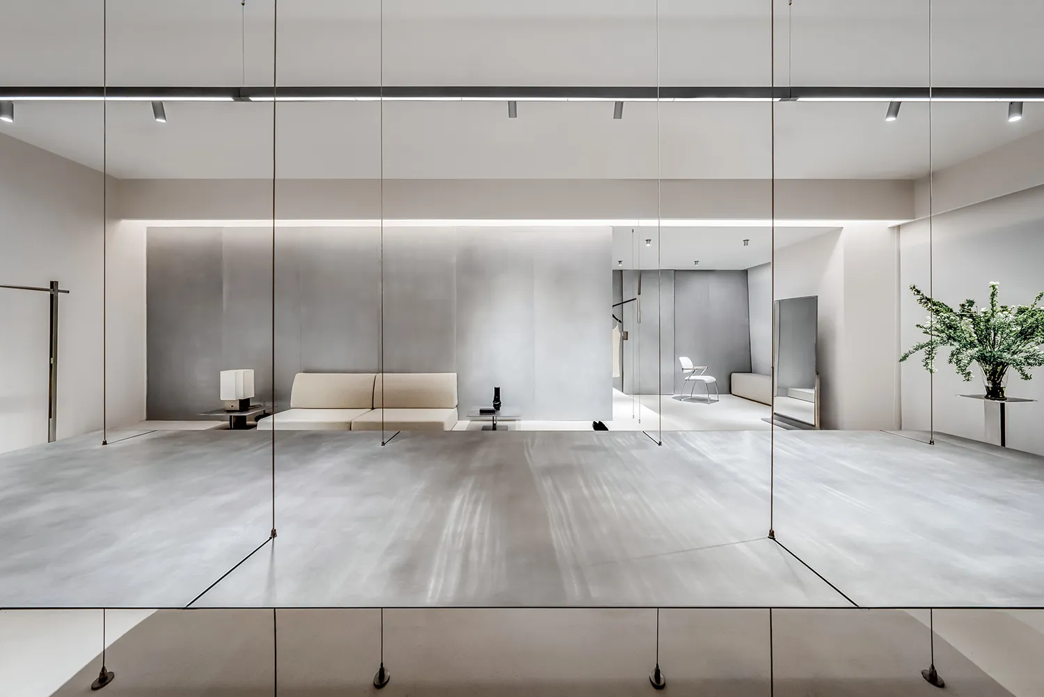 Minimalist installation featuring glass panels on a metallic floor and white walls.