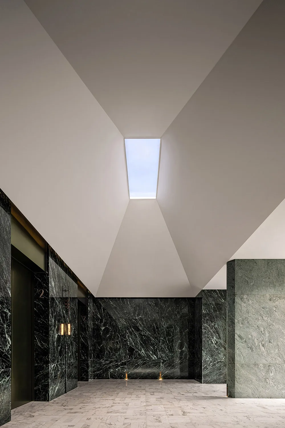 A modern lobby featuring marble floors and concrete walls.
